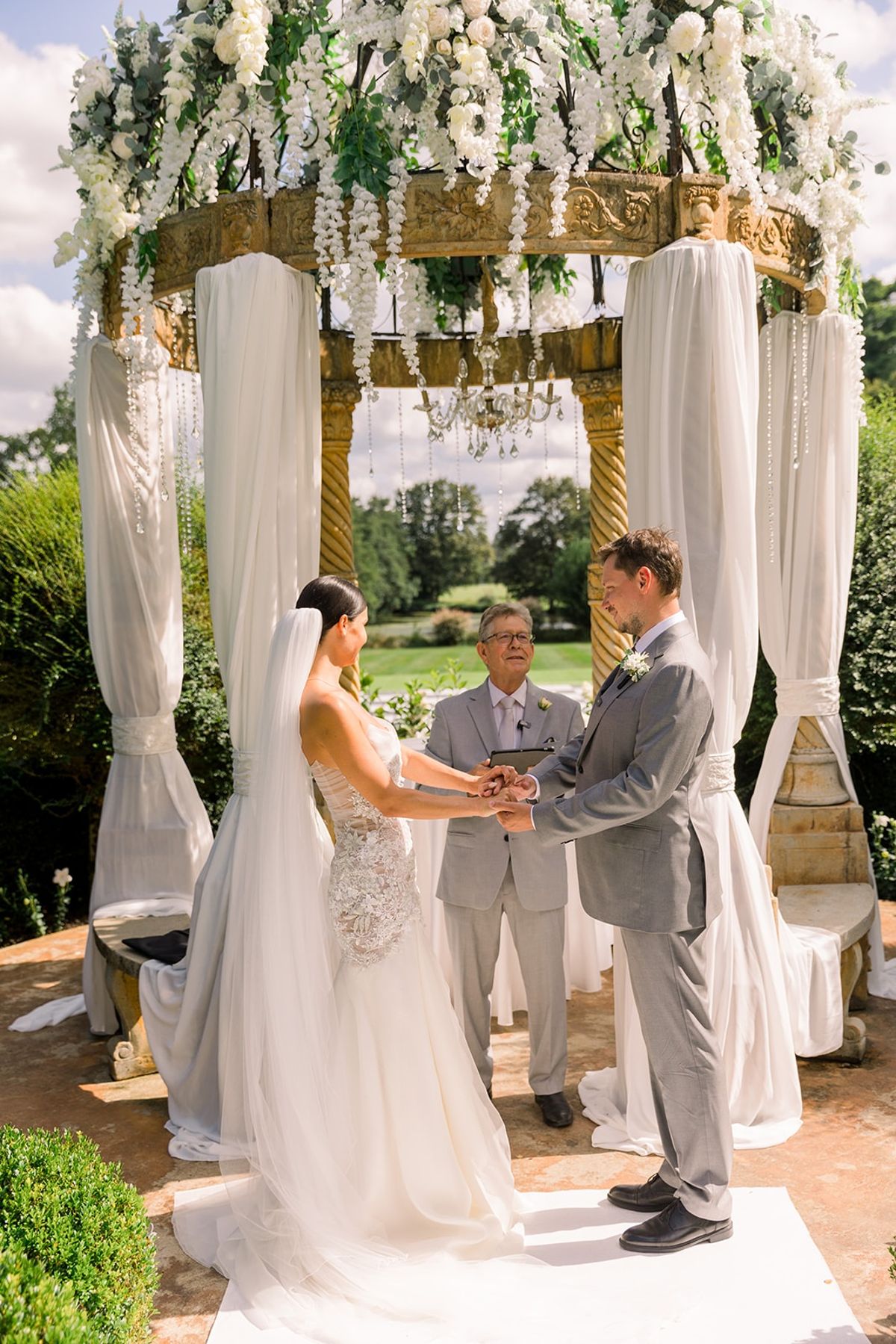 Couple exchanging vows beneath floral pavilion arch at Chateau Challain, Loire Valley
