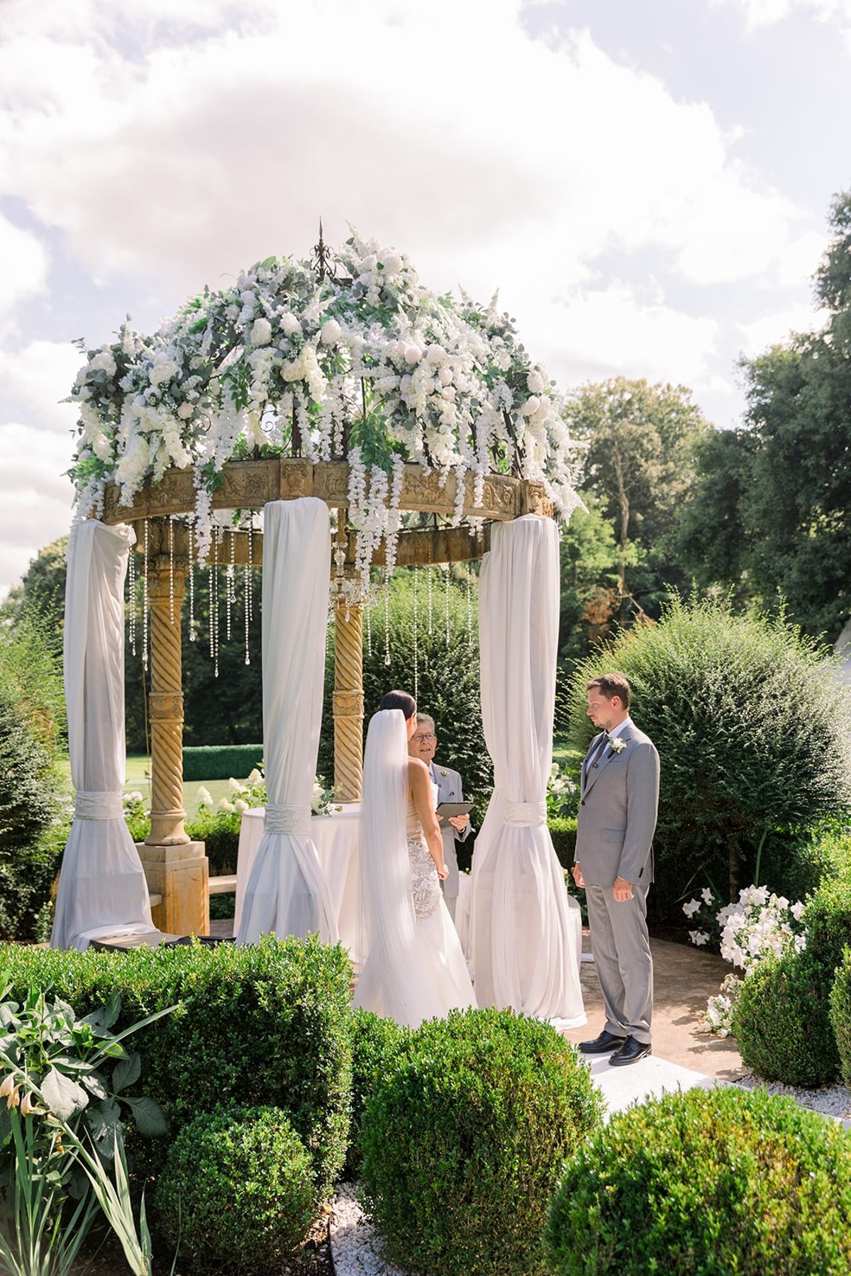 Couple at floral pavilion altar during ceremony at Chateau Challain, Loire Valley