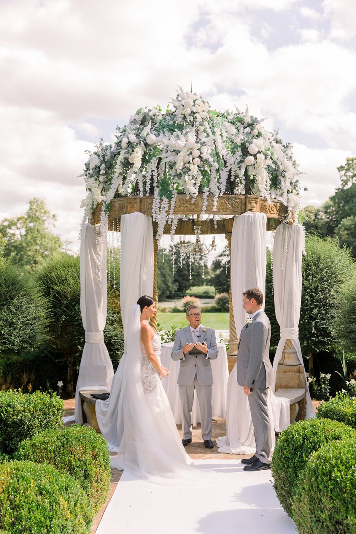 Couple at ceremony beneath wisteria pavilion at Chateau Challain, Loire Valley