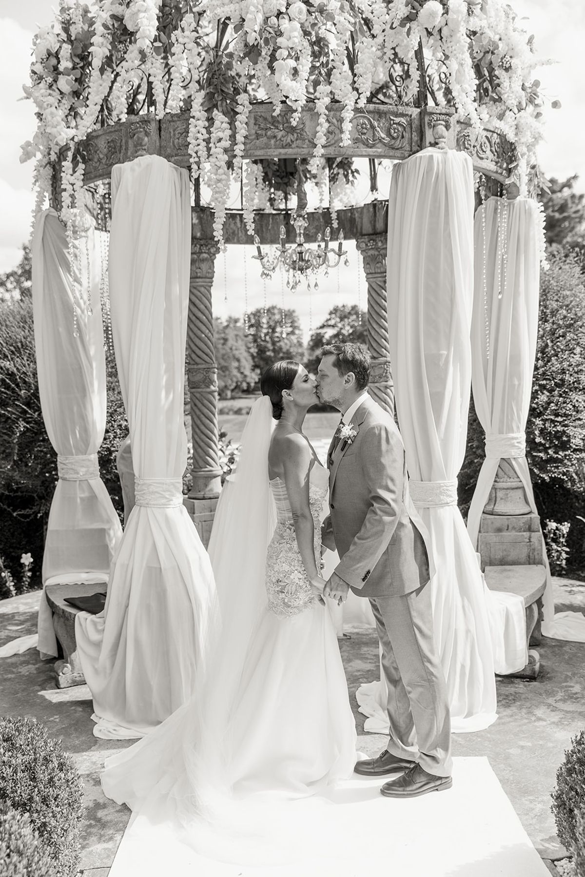 Couple kissing beneath floral pavilion arch at Chateau Challain, Loire Valley