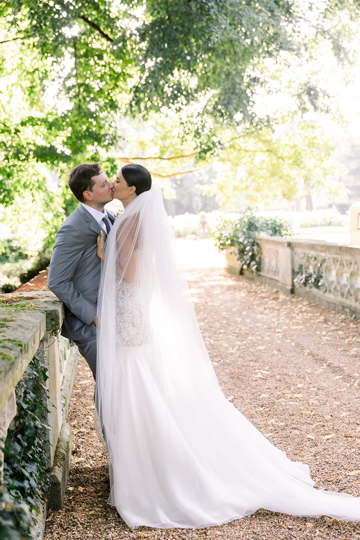 Couple kissing on stone bridge beneath trees at Chateau Challain, Loire Valley