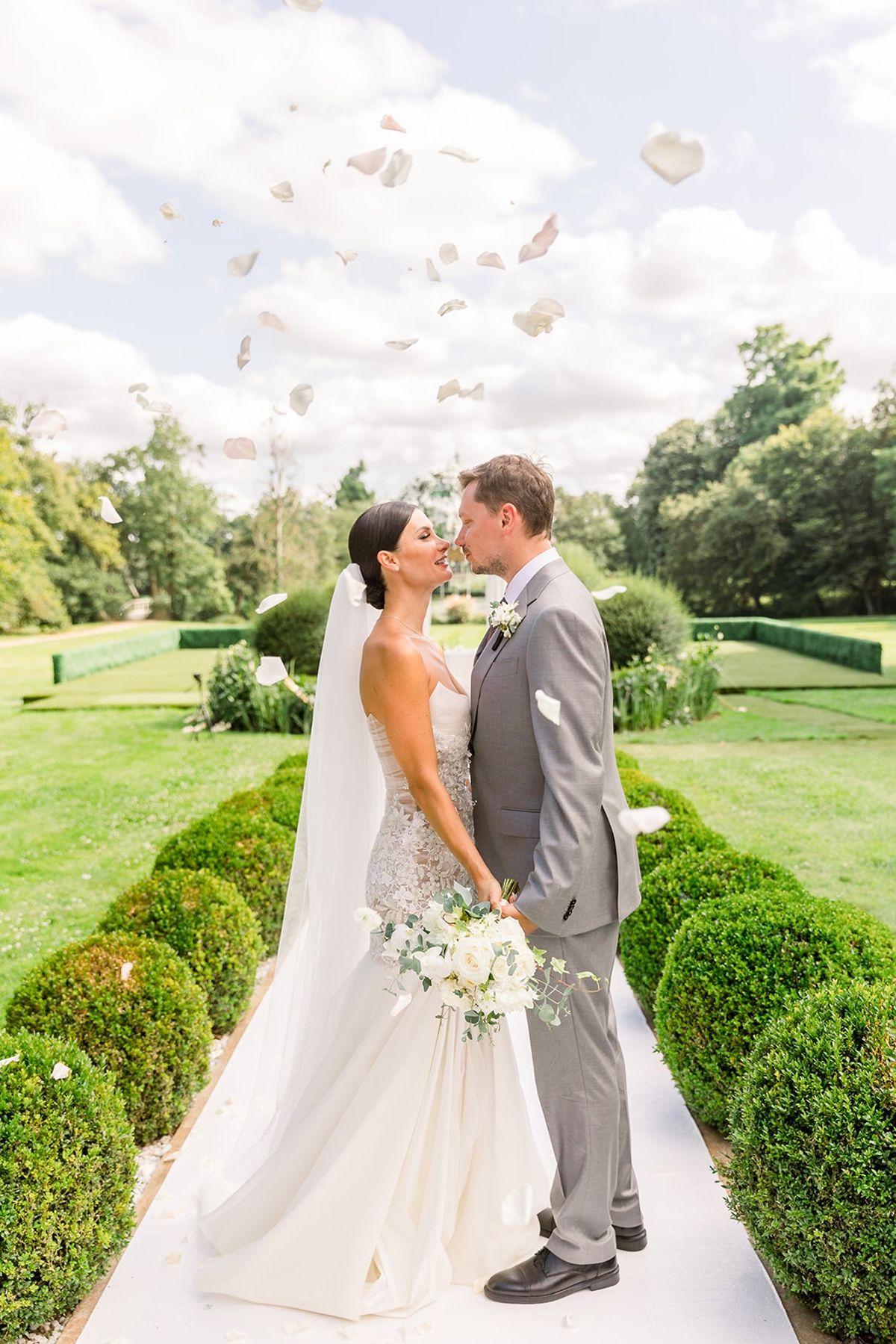 Couple sharing a kiss in petal toss on aisle at Chateau Challain, Loire Valley