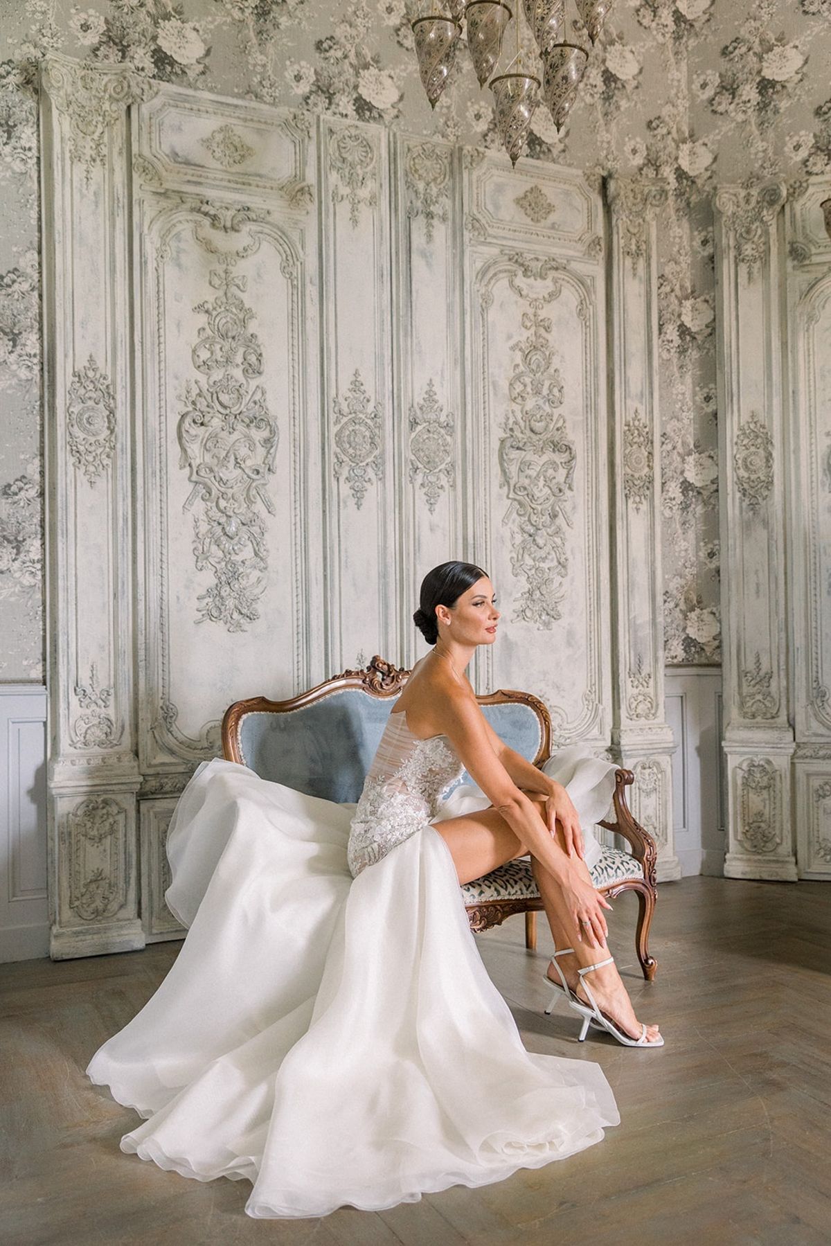 Bride seated on carved settee in vintage panelled room at Chateau Challain, Loire Valley