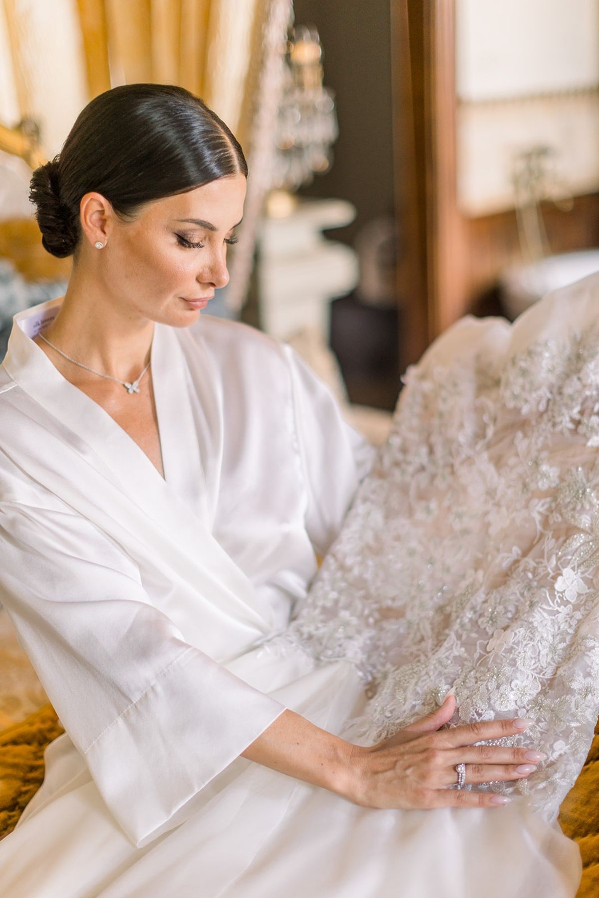 Bride in silk robe holding wedding gown before dressing at Chateau Challain, Loire Valley