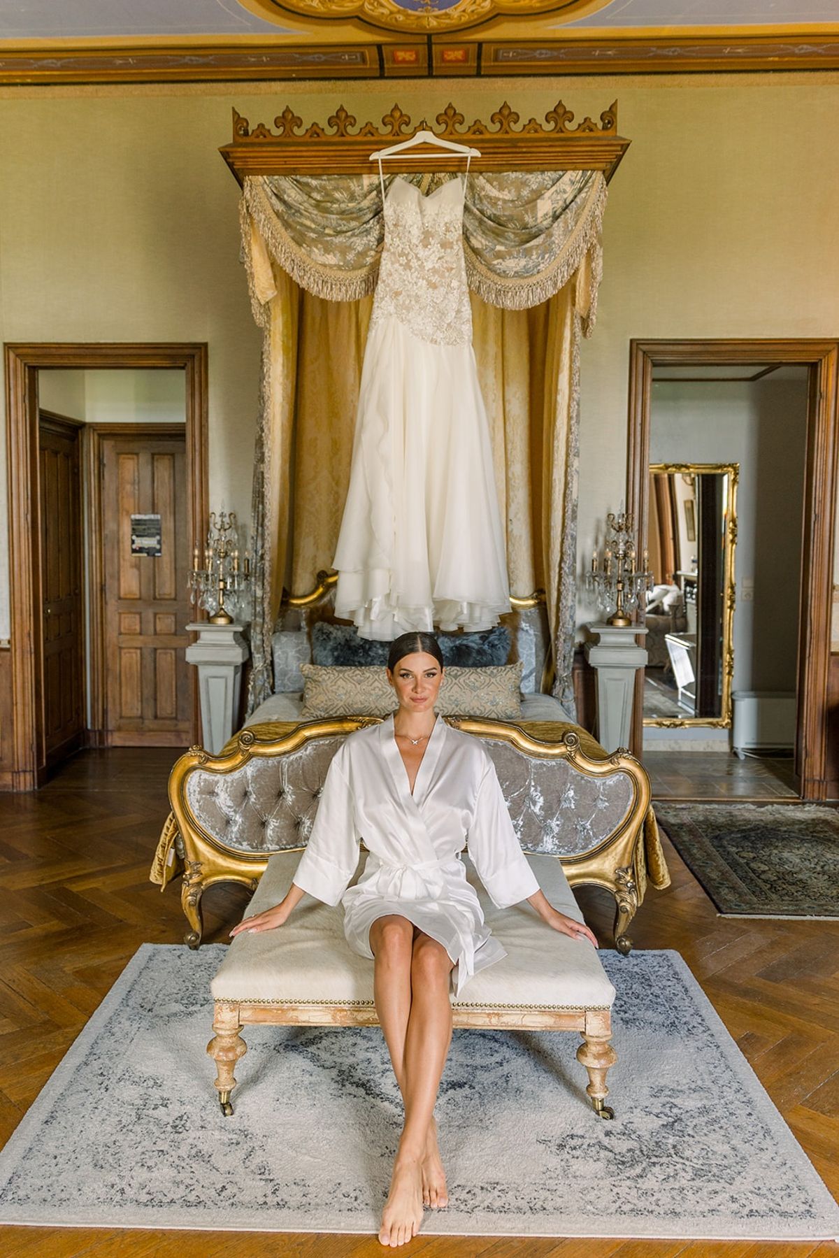 Bride in silk robe with hanging wedding dress at Chateau Challain, Loire Valley