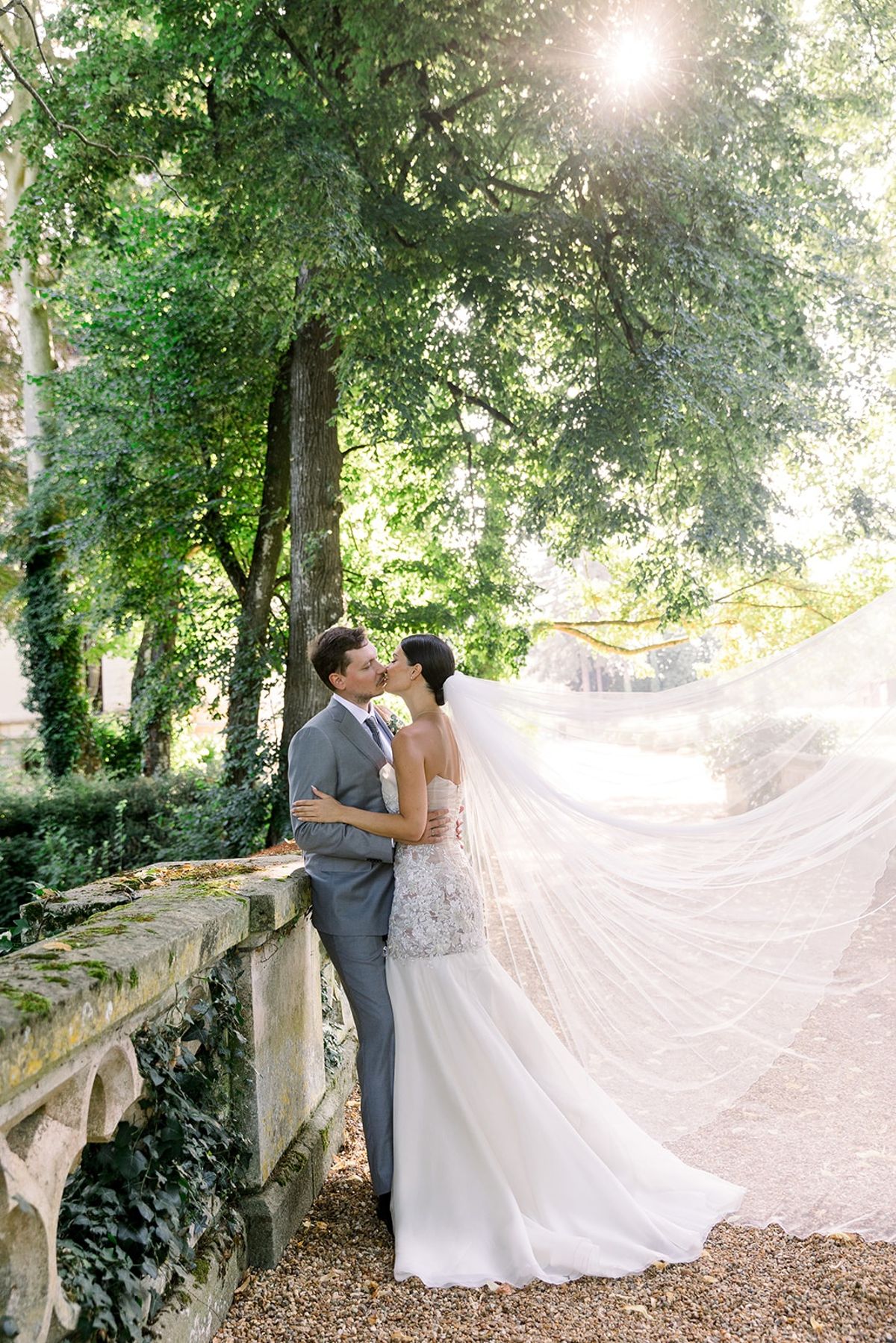 Couple kissing under sunbeam on stone balustrade at Chateau Challain, Loire Valley