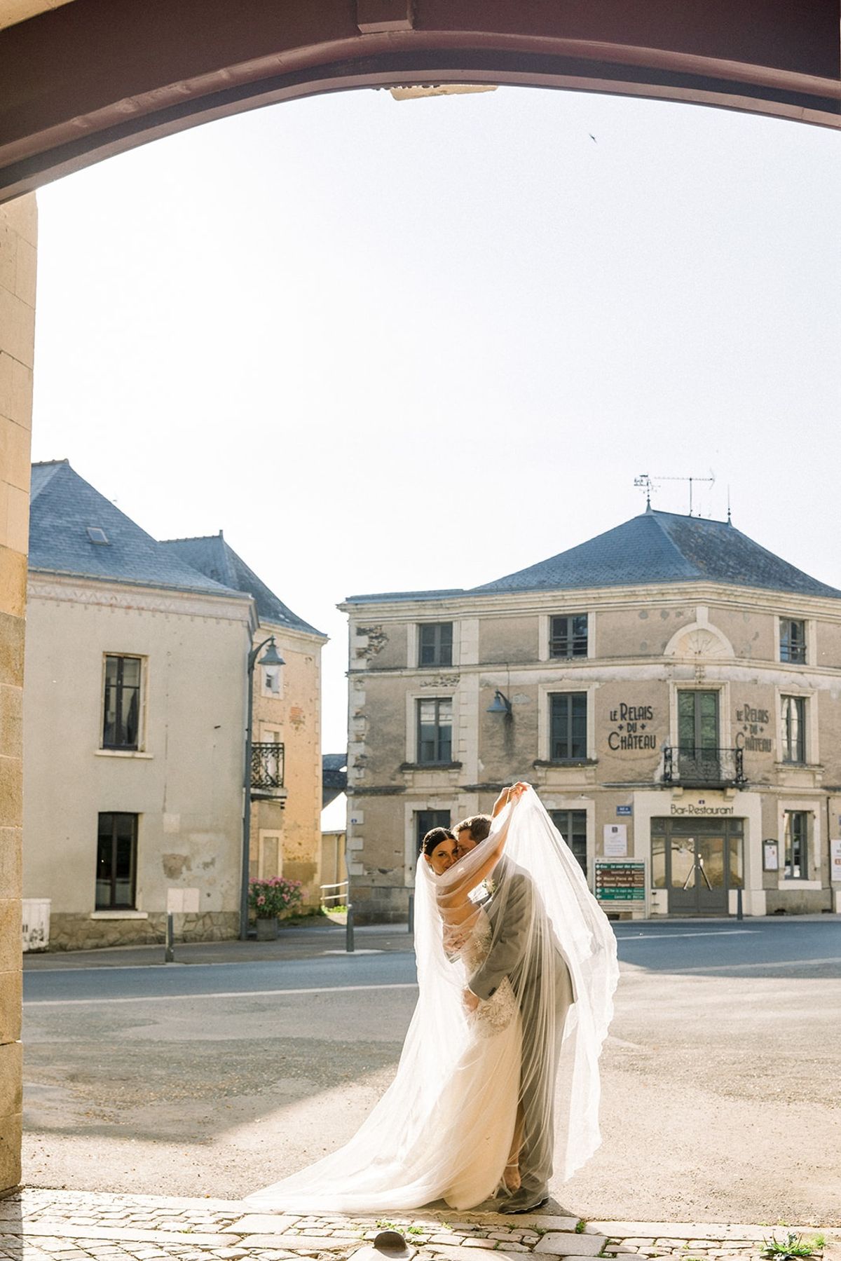 Couple kissing under veil through stone archway at Chateau Challain, Loire Valley