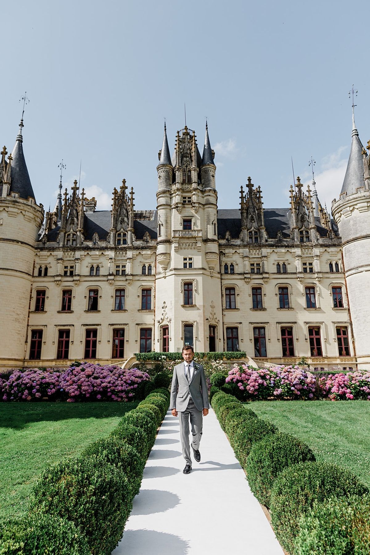 Groom walking toward chateau facade at Chateau Challain, Loire Valley