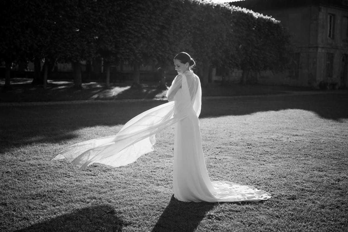 The bride's veil lifting in the wind on the lawn, in black and white
