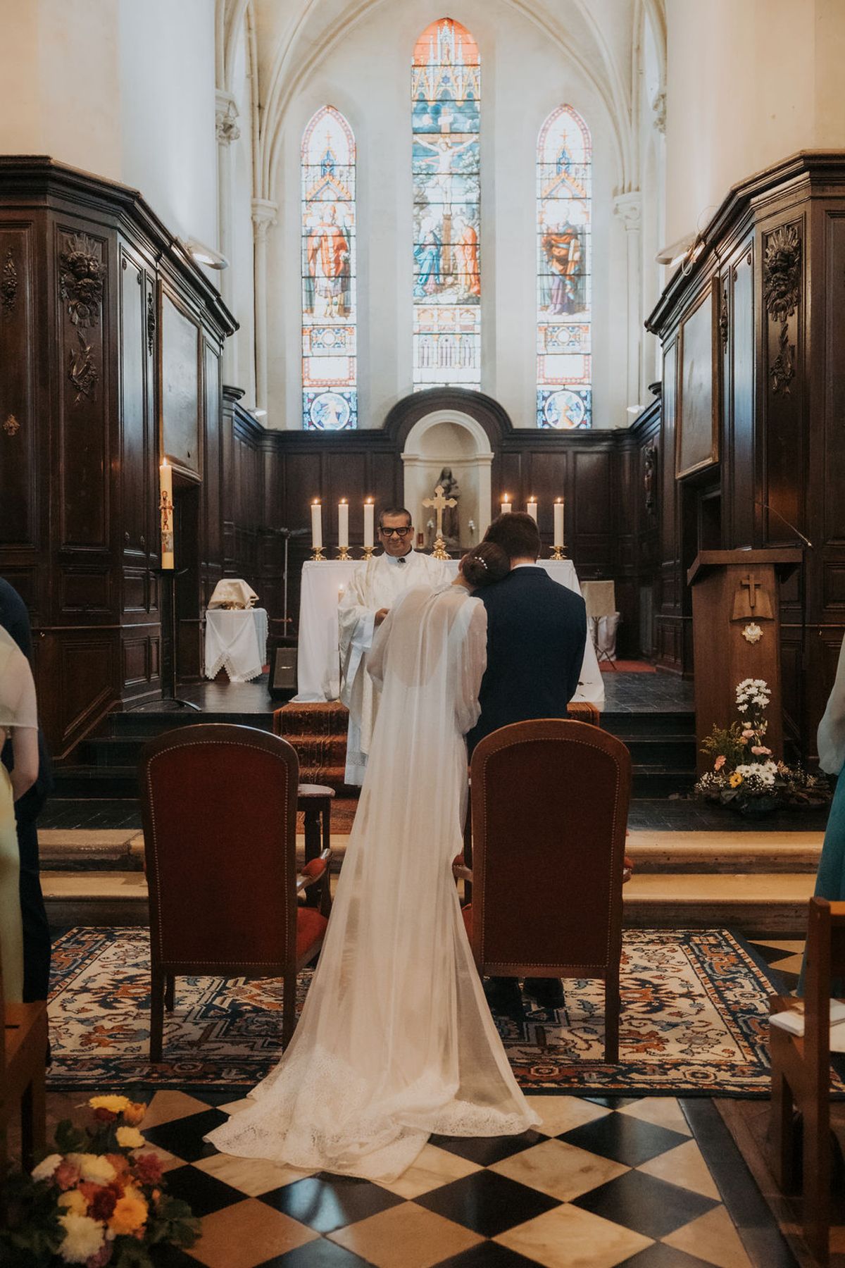 The bride and groom at the altar of a church with stained-glass windows