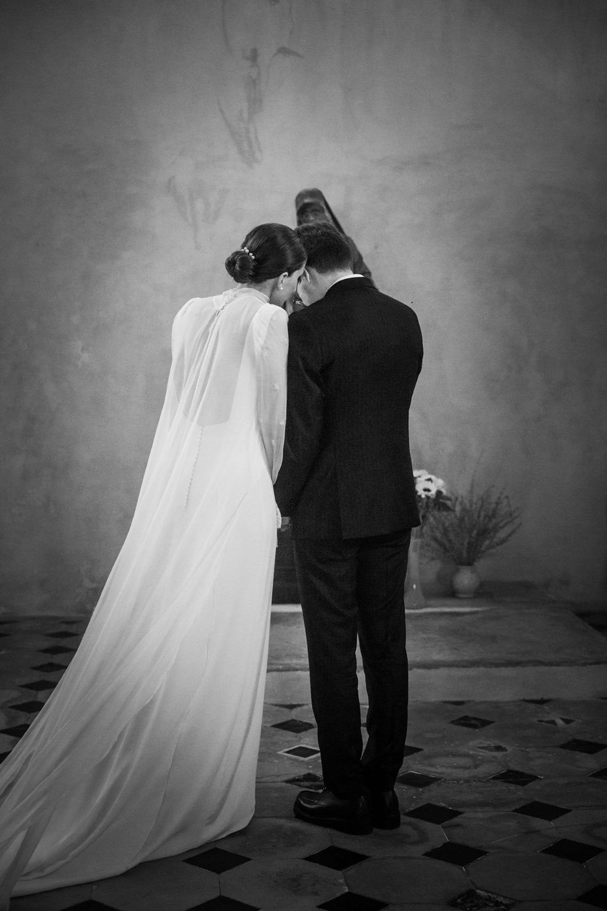 The bride and groom side by side in a church, seen from behind, in black and white