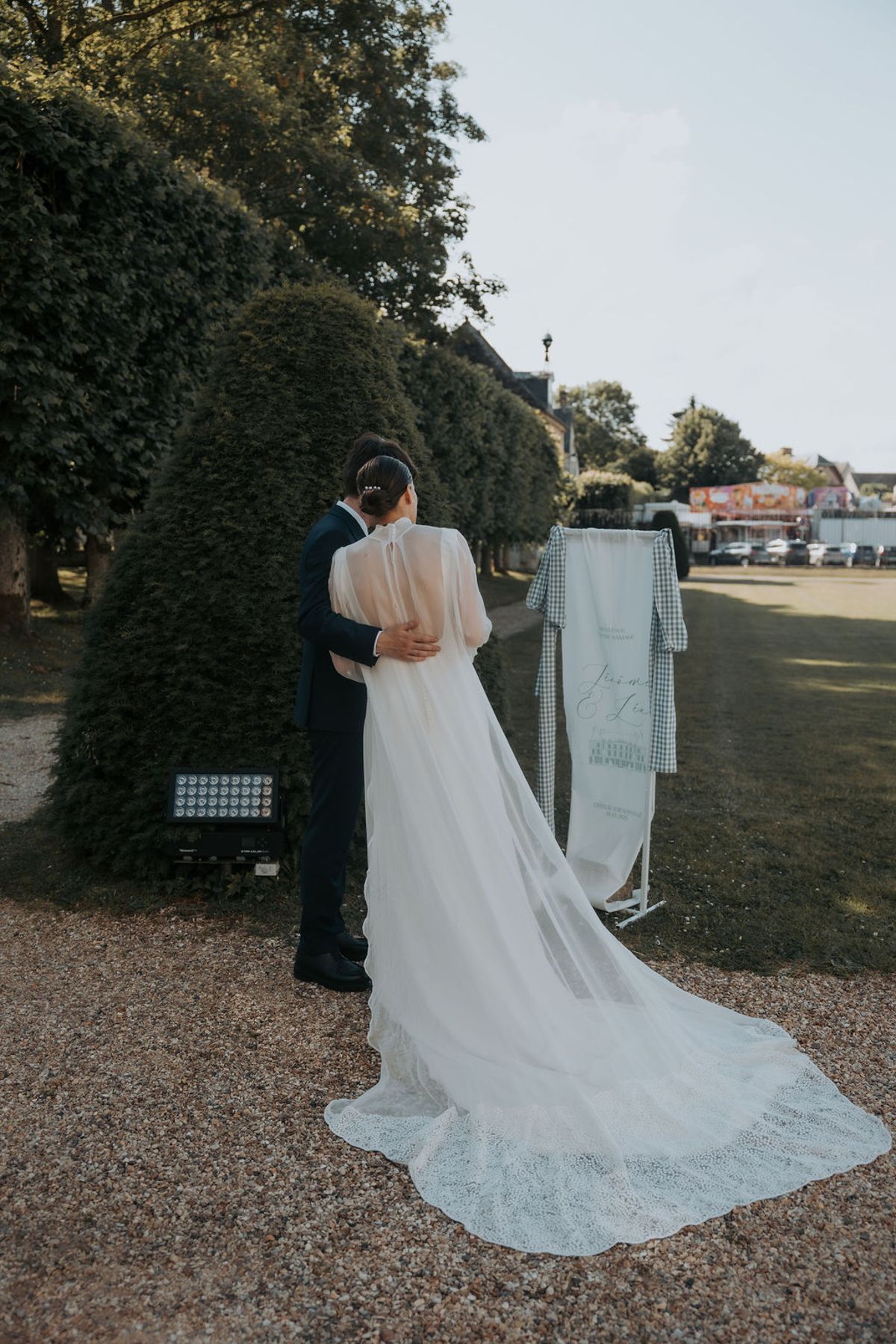 The bride and groom by a clipped hedge, seen from behind