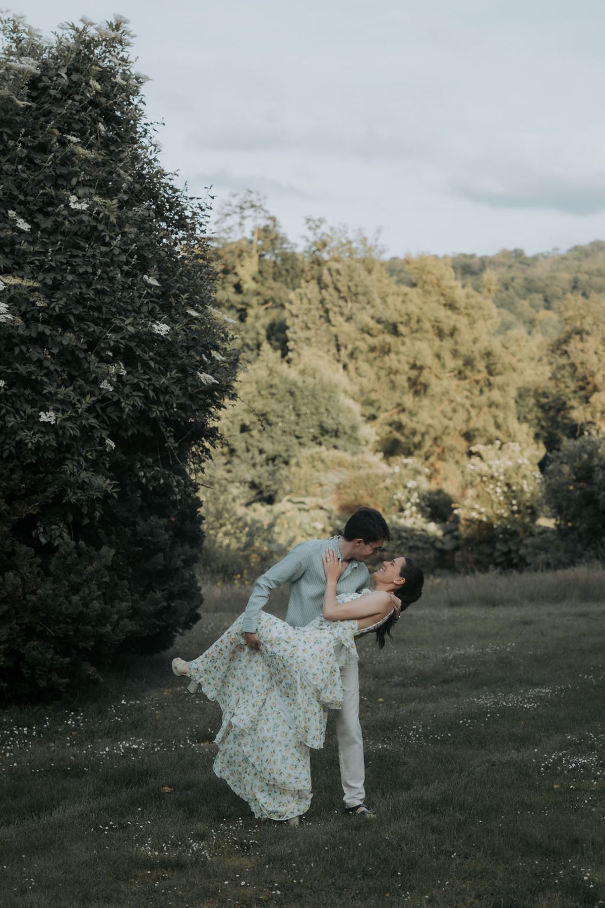 The groom dips the bride for a kiss in a meadow, the evening before the wedding