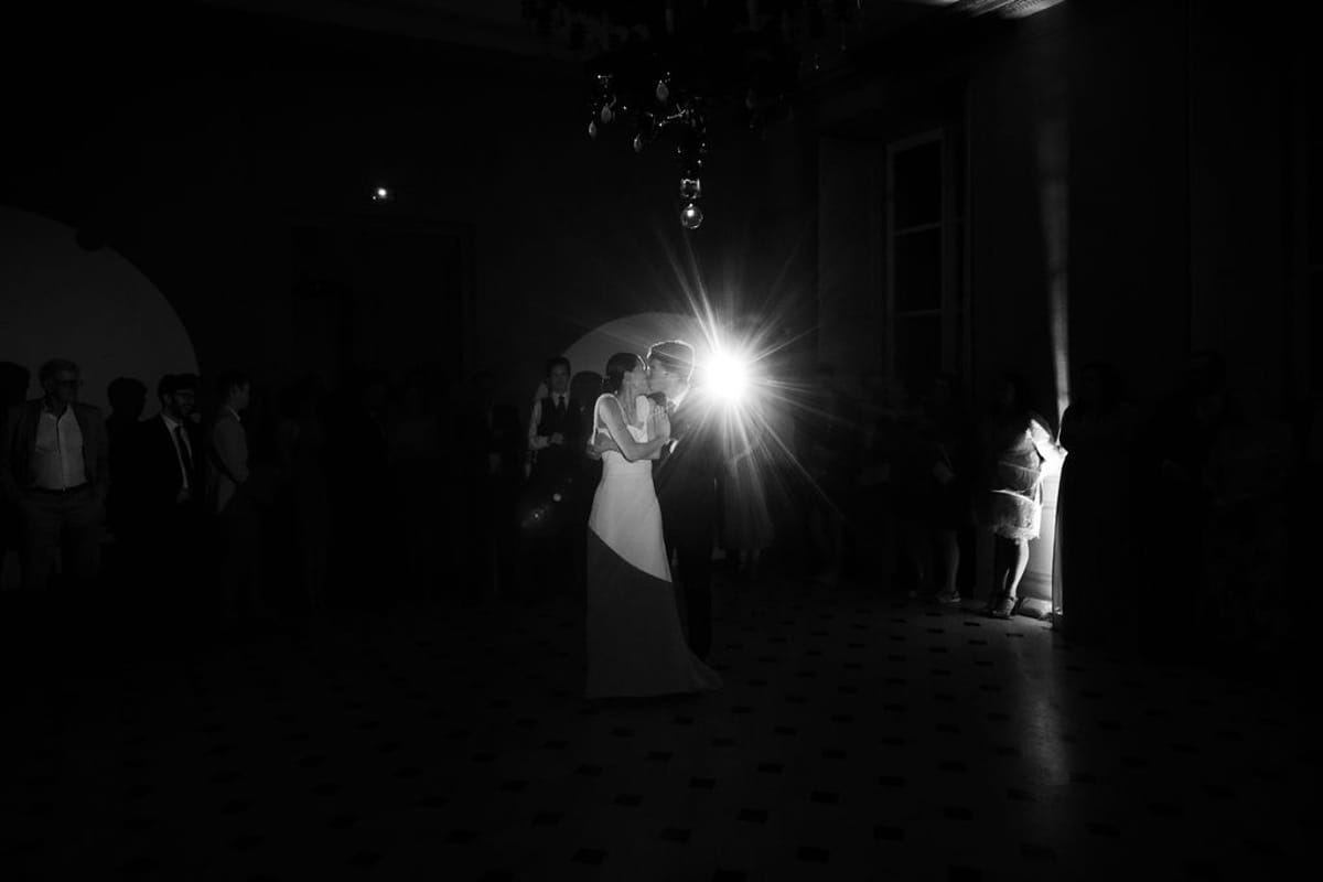 The bride and groom on the dance floor lit by a single light, in black and white