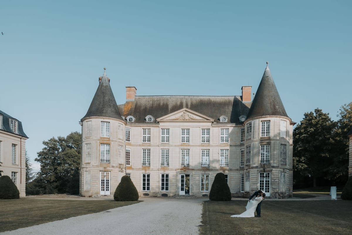 Château d'Hénonville across the lawn, with the bride and groom small in the distance