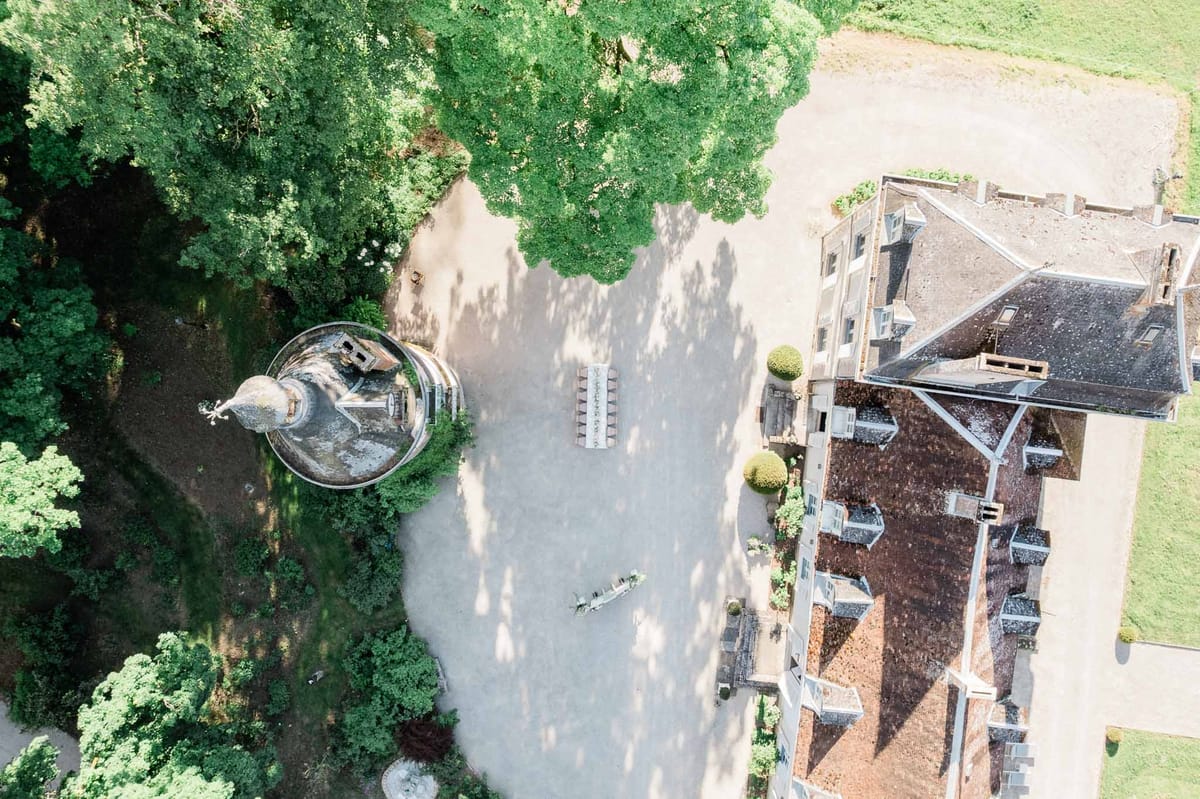 Aerial view of historic stone château with formal gardens and courtyard