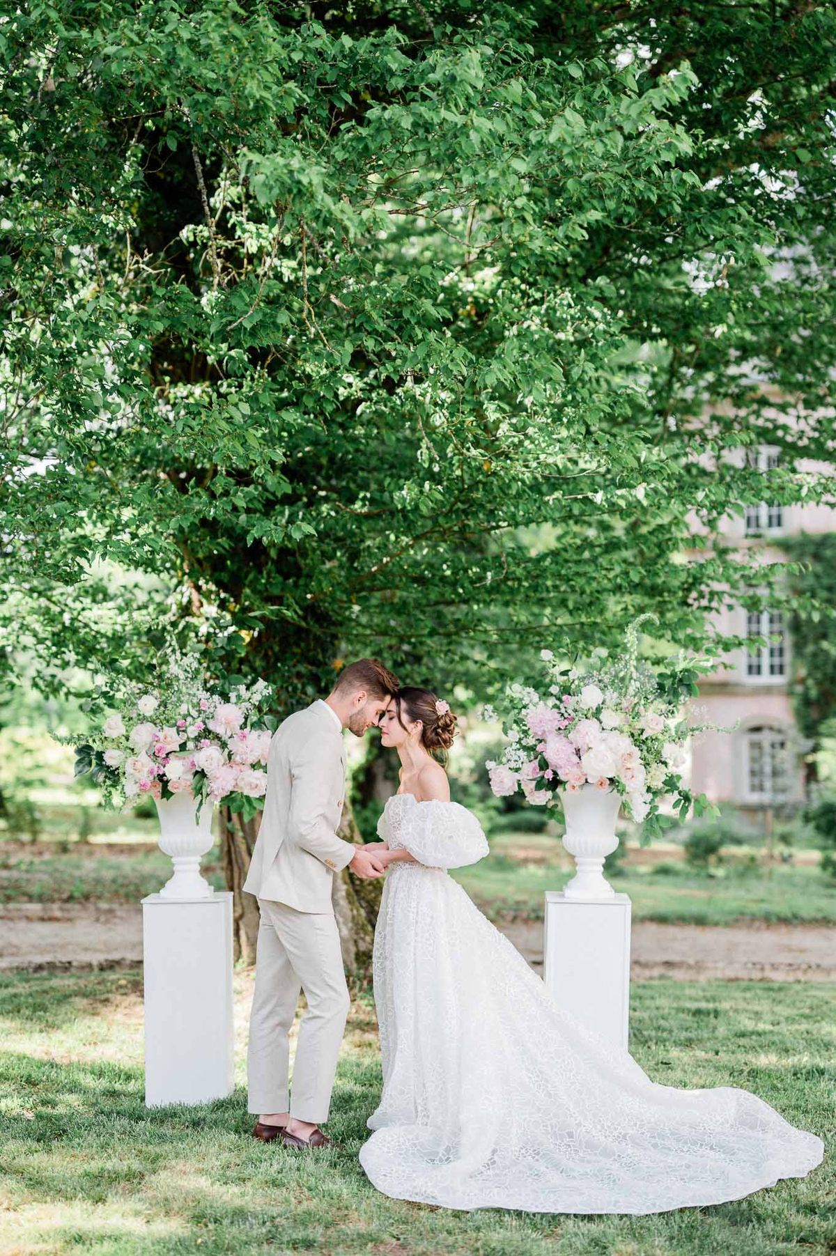 Bride and groom portrait beneath floral arbor in classical garden courtyard