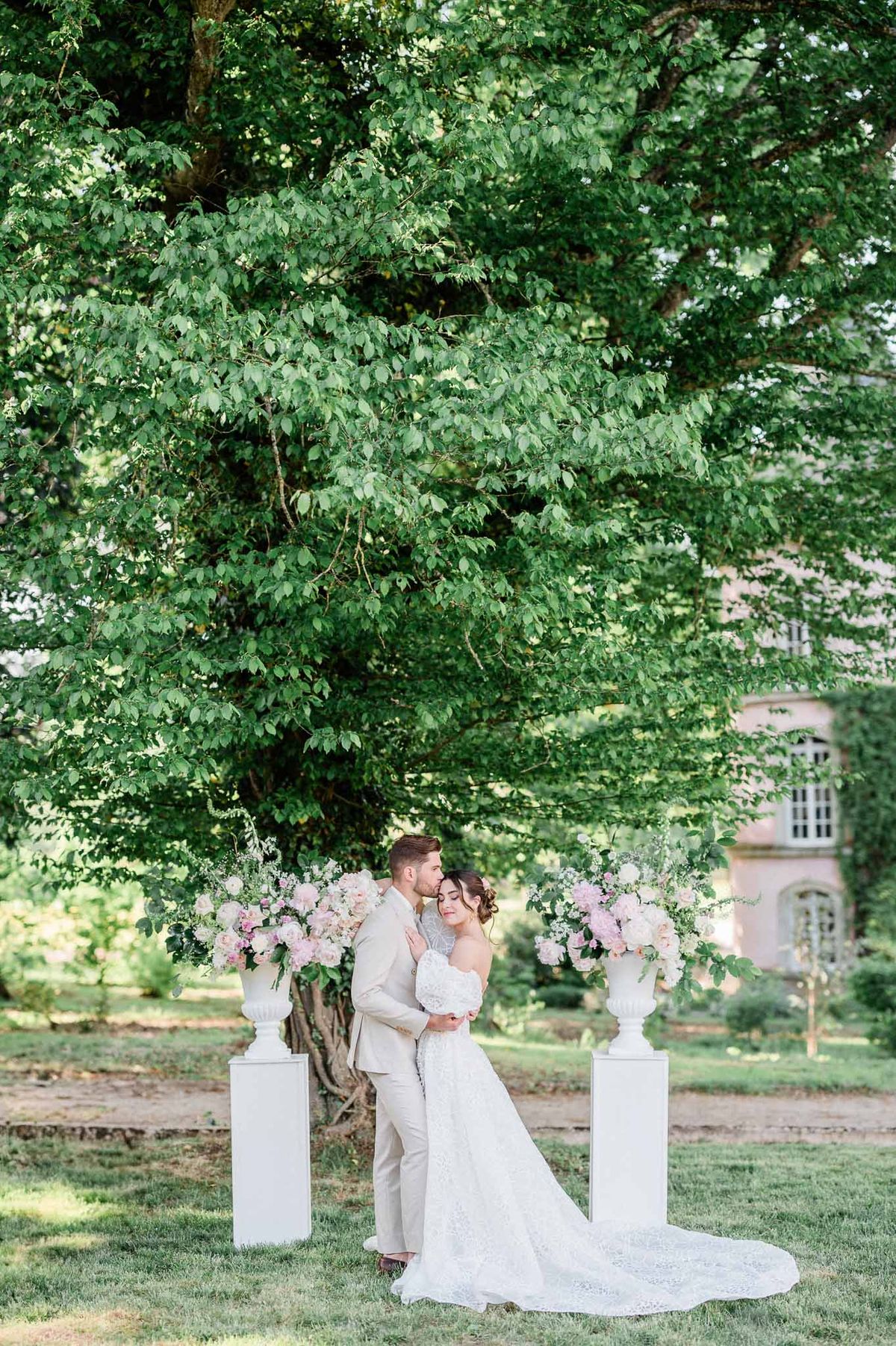 Bride and groom portrait in garden setting with floral arrangements at chateau venue