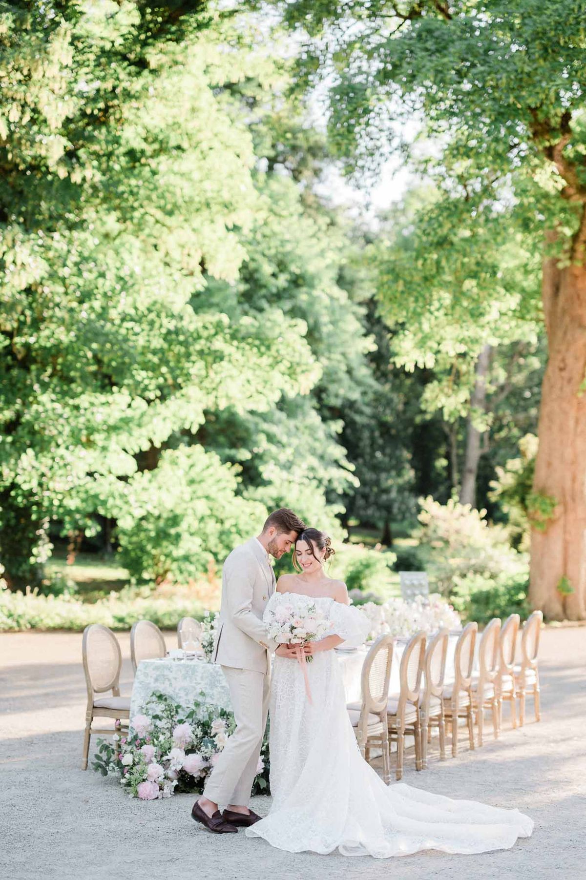 Bride and groom during outdoor ceremony on terrace with wooden chairs and natural tree canopy