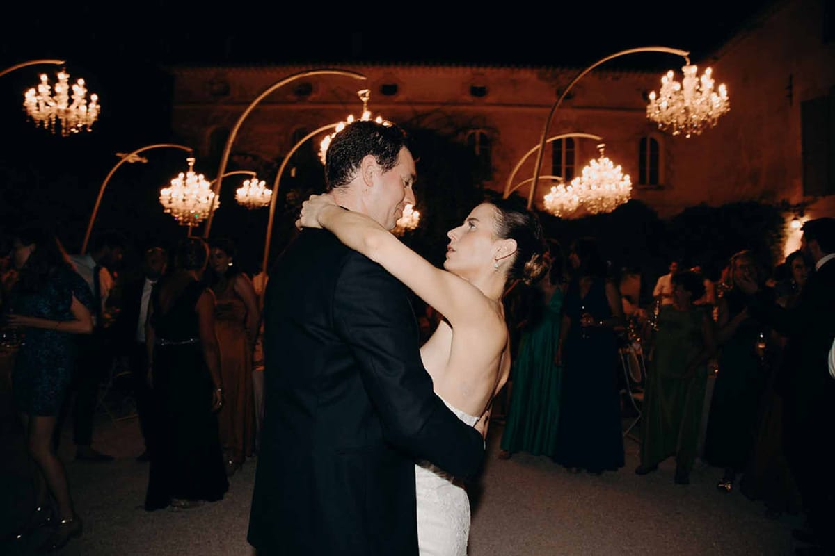 Bride and groom share first dance under gold arched chandeliers at outdoor evening chateau reception