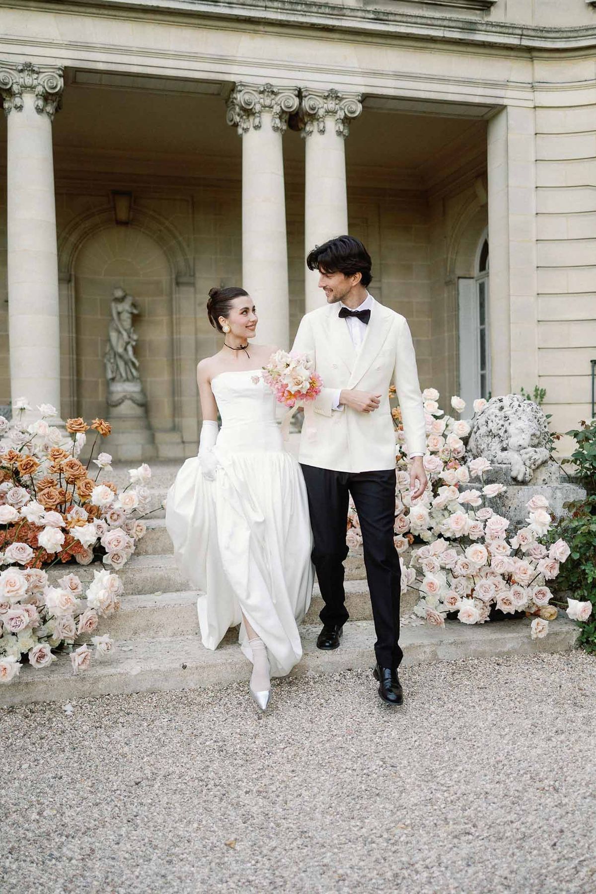 Bride and groom walking hand in hand in a garden