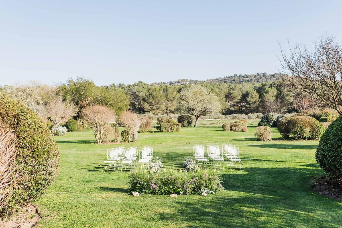 Outdoor wedding ceremony setup with white chairs on garden lawn at estate venue