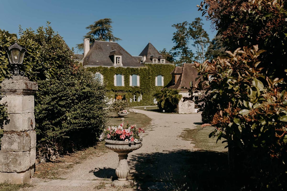 Stone fountain with pink flowers at ivy-covered entrance to Domaine de la Fauconnie