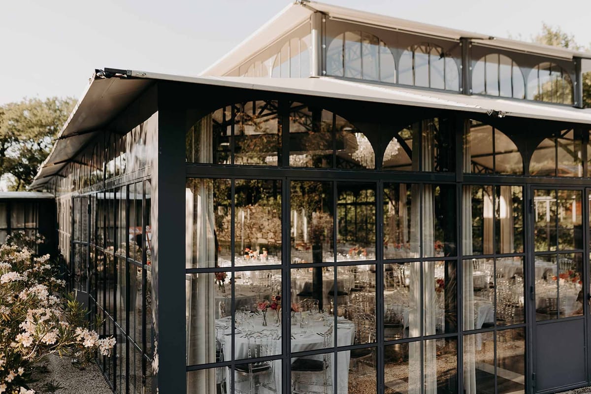 Glass orangery exterior with reception tables visible at Domaine de la Fauconnie