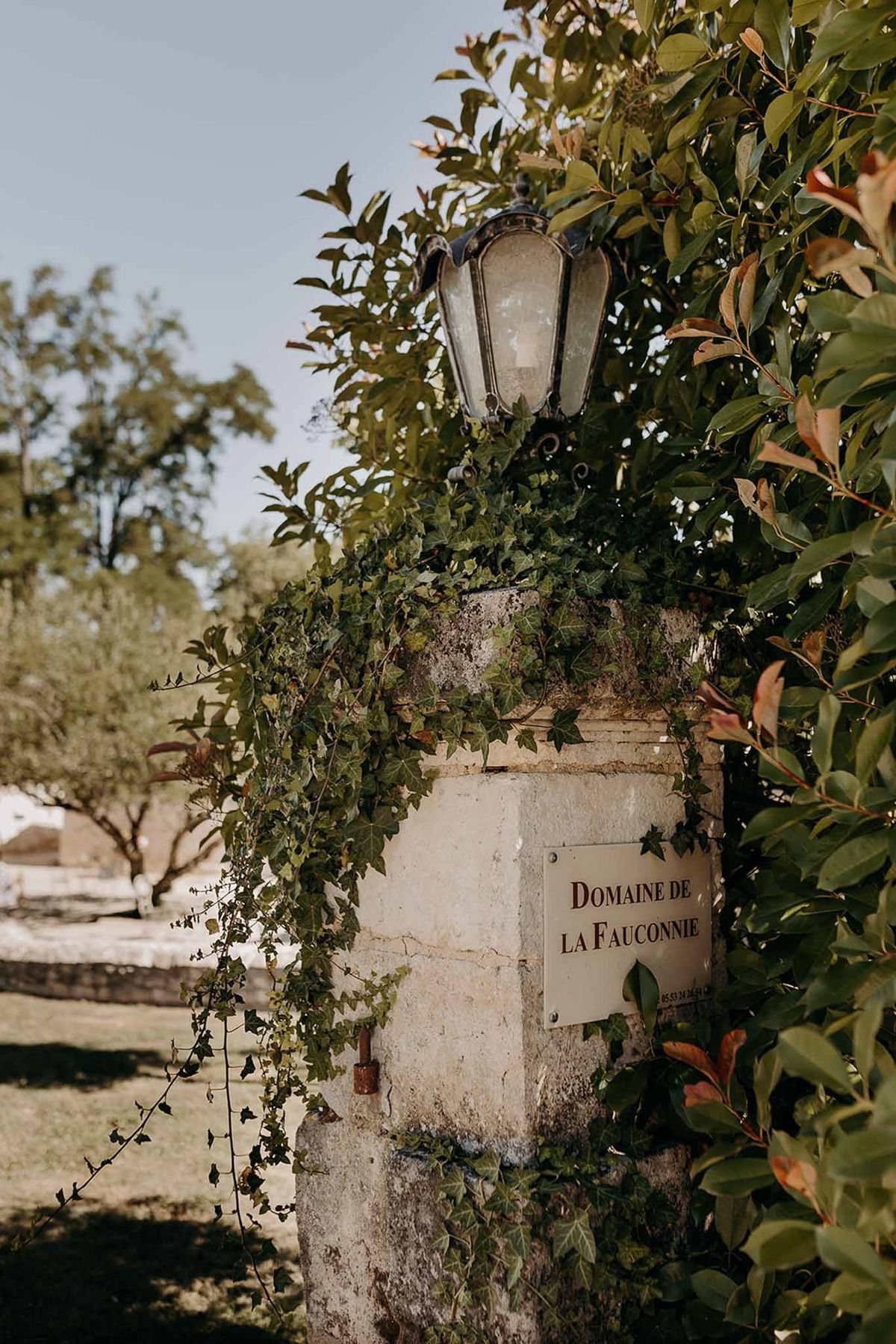 Entrance pillar with name sign and vintage lamp at Domaine de la Fauconnie