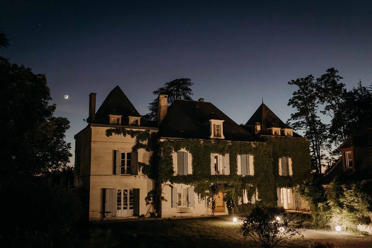 Domaine de la Fauconnie château lit up at night under crescent moon