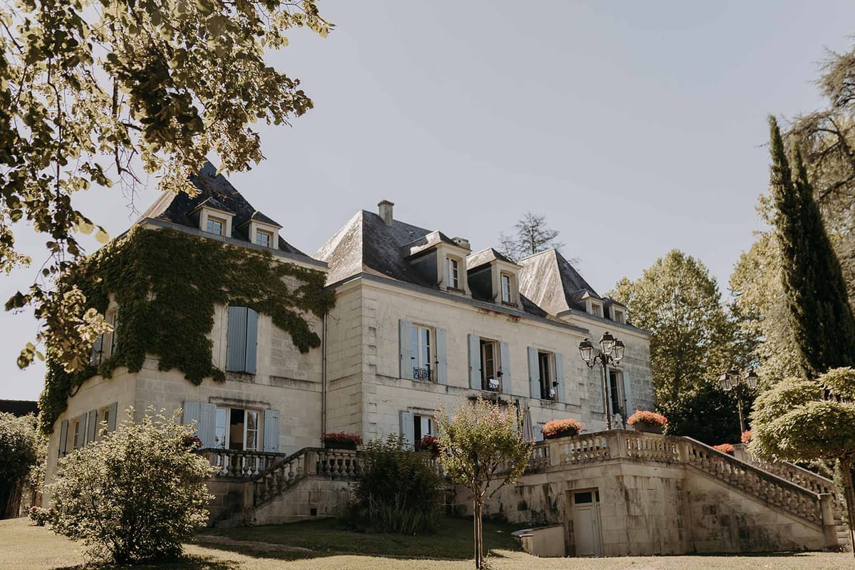 Front view of Domaine de la Fauconnie with stone staircase and blue shutters