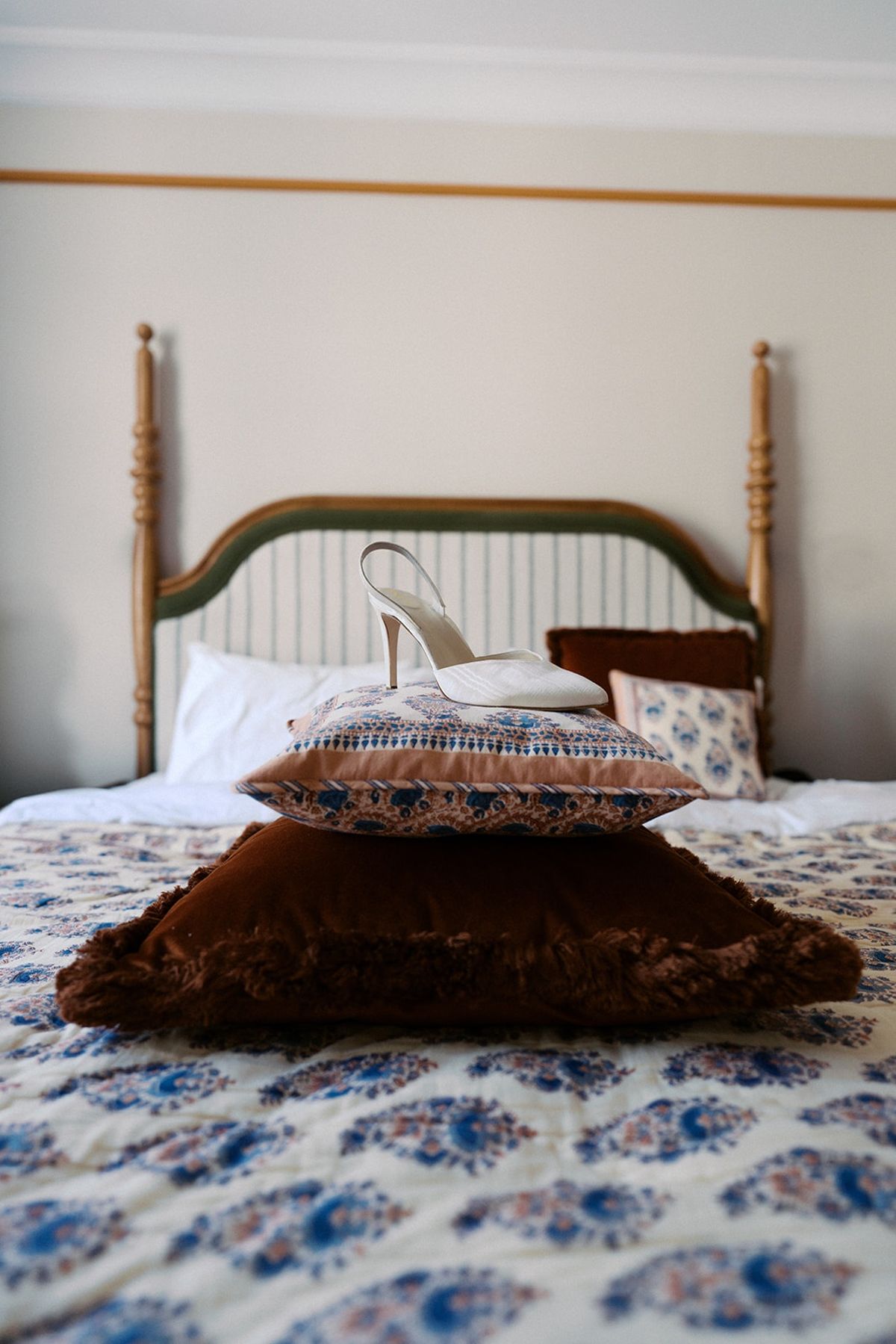 White slingback bridal shoe on stacked vintage cushions on a hotel bed in Paris