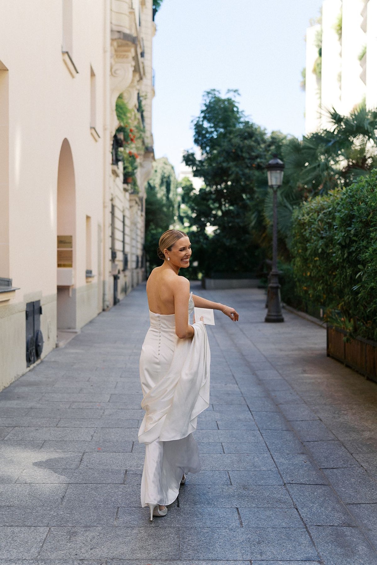 Bride glances back over her shoulder while walking a Paris side street in her ivory gown