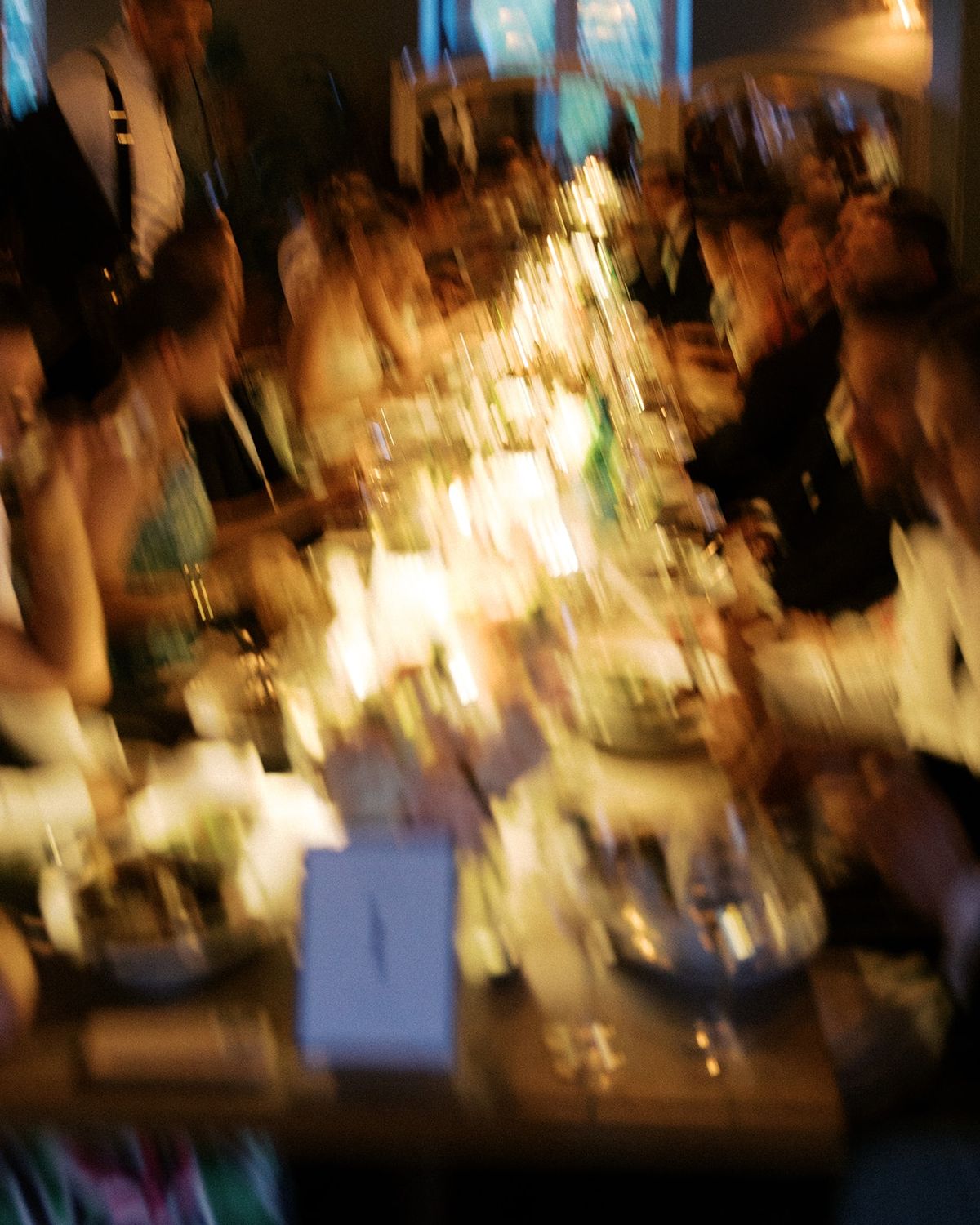 Motion-blurred long reception table with candles, florals, and seated guests at Restaurant l'Ile