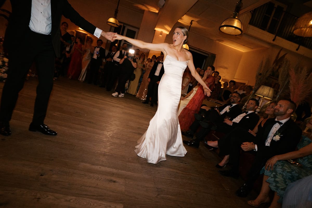 Bride mid-twirl during the first dance, the groom's arm reaching toward her
