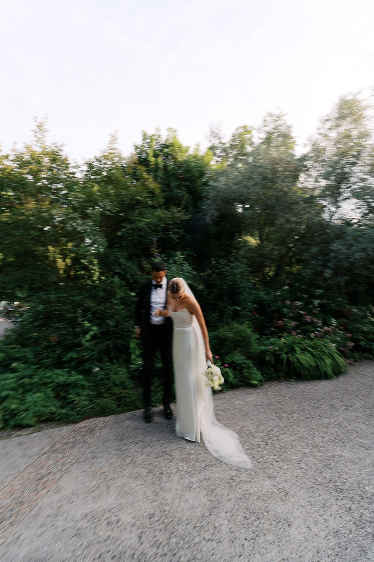 Couple walking through the garden in soft motion, the bride holding her bouquet