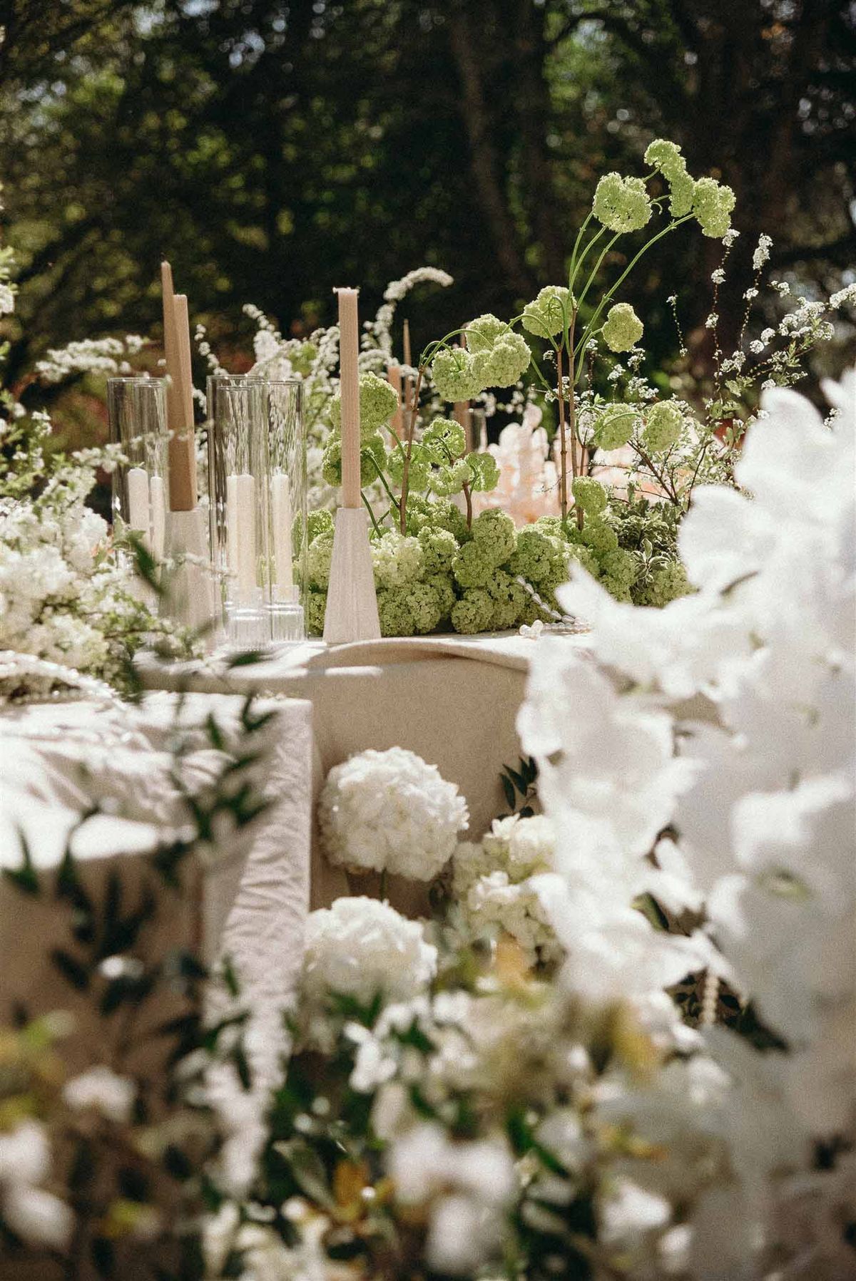 Garden reception table with white peony and orchid centerpiece and ivory taper candles
