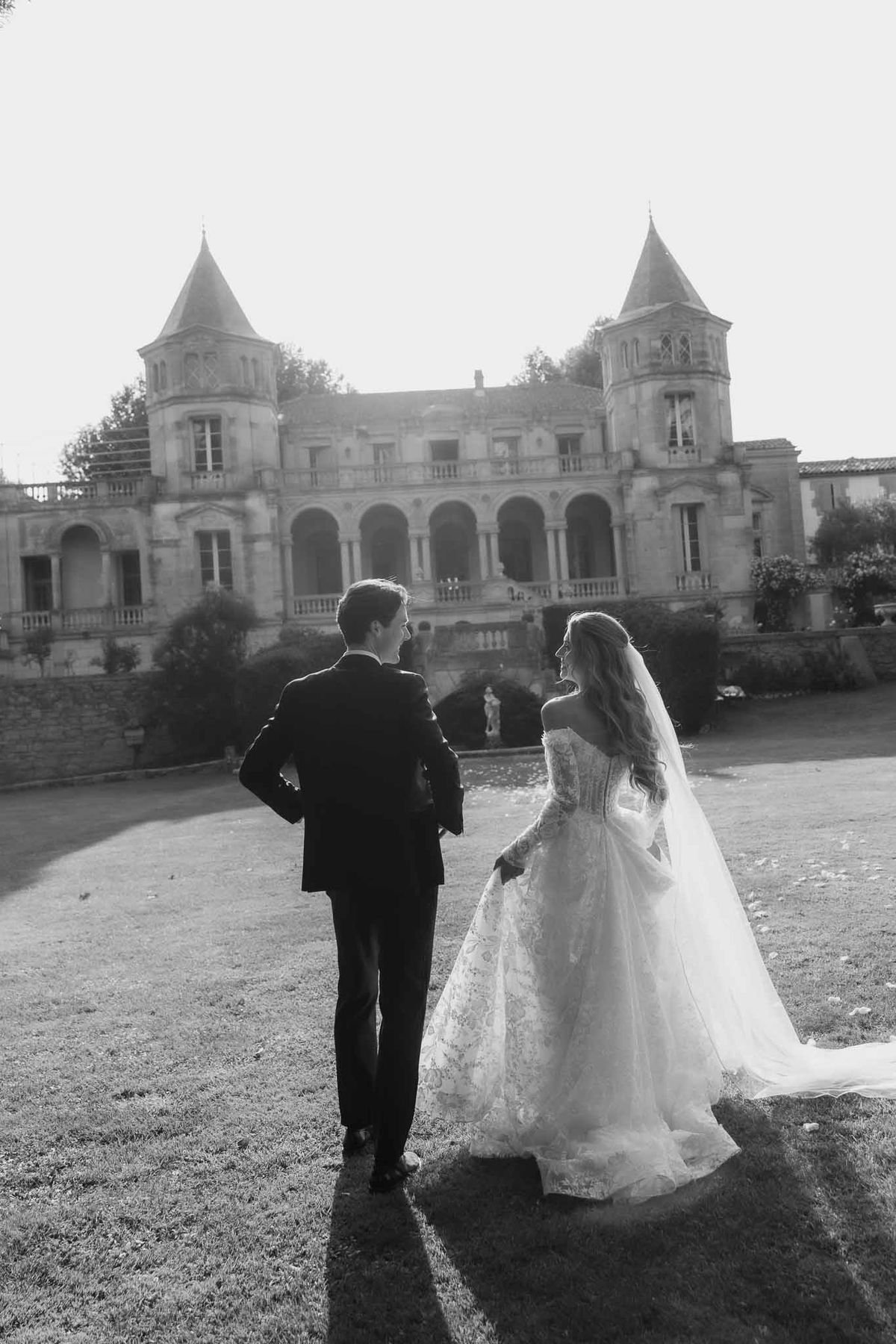 Black and white photo of bride and groom walking hand in hand