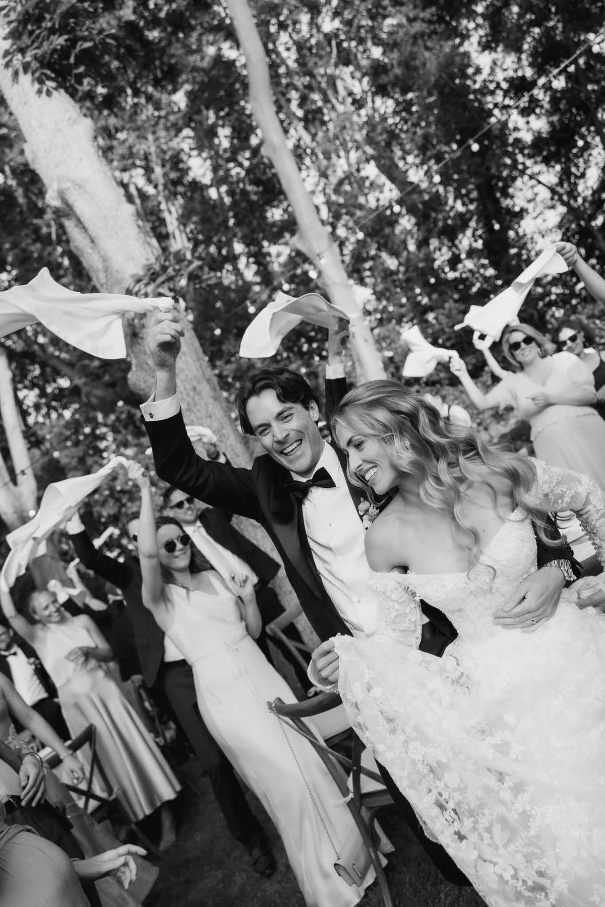 Black and white recessional with guests waving white napkins as bride and groom walk down aisle