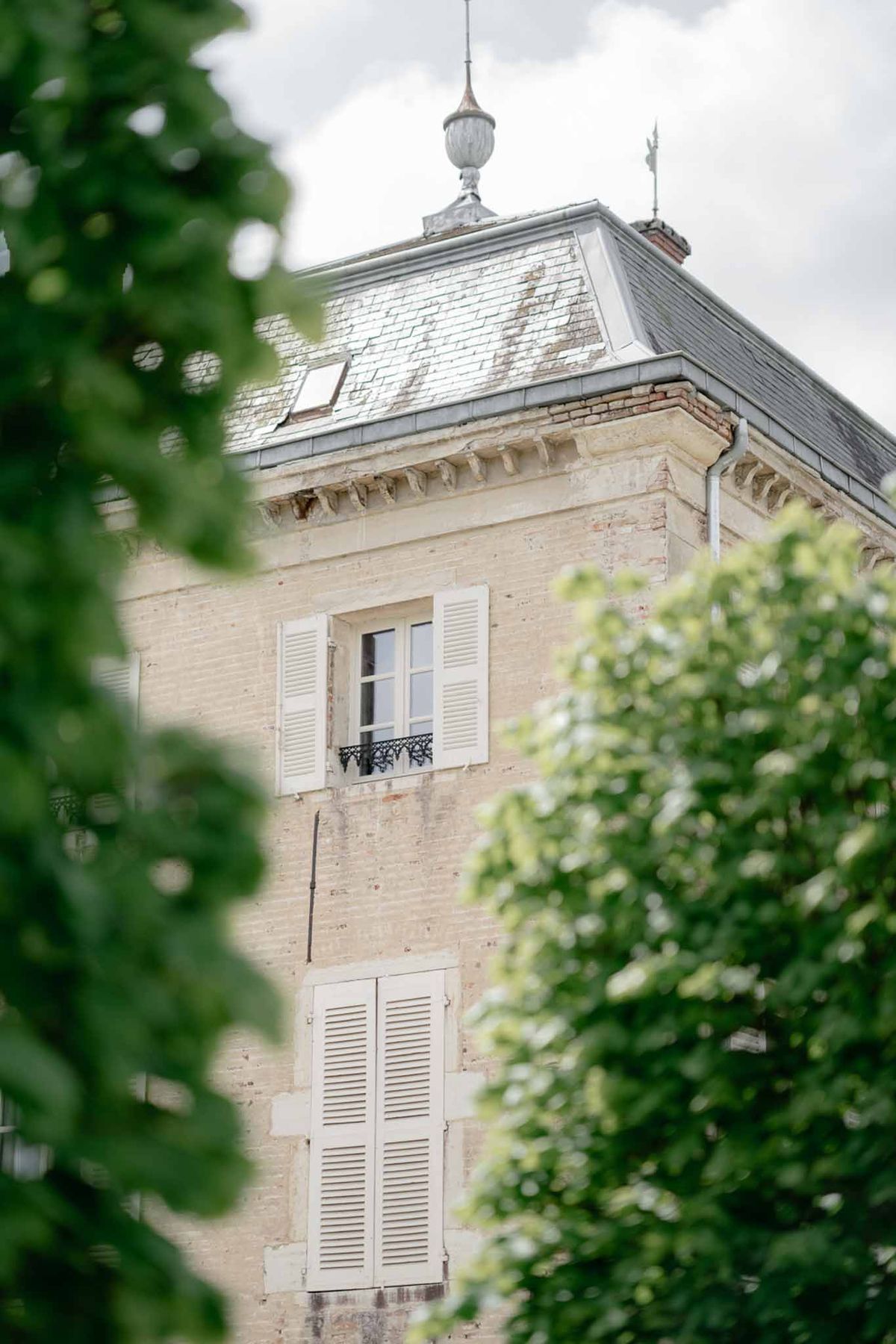 Chateau tower with cream stone louvered shutters wrought-iron balcony and slate mansard roof