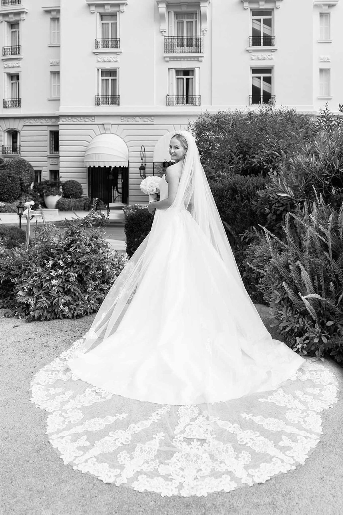 Black and white bride with cathedral lace-trimmed veil and peony bouquet before Haussmann palace facade