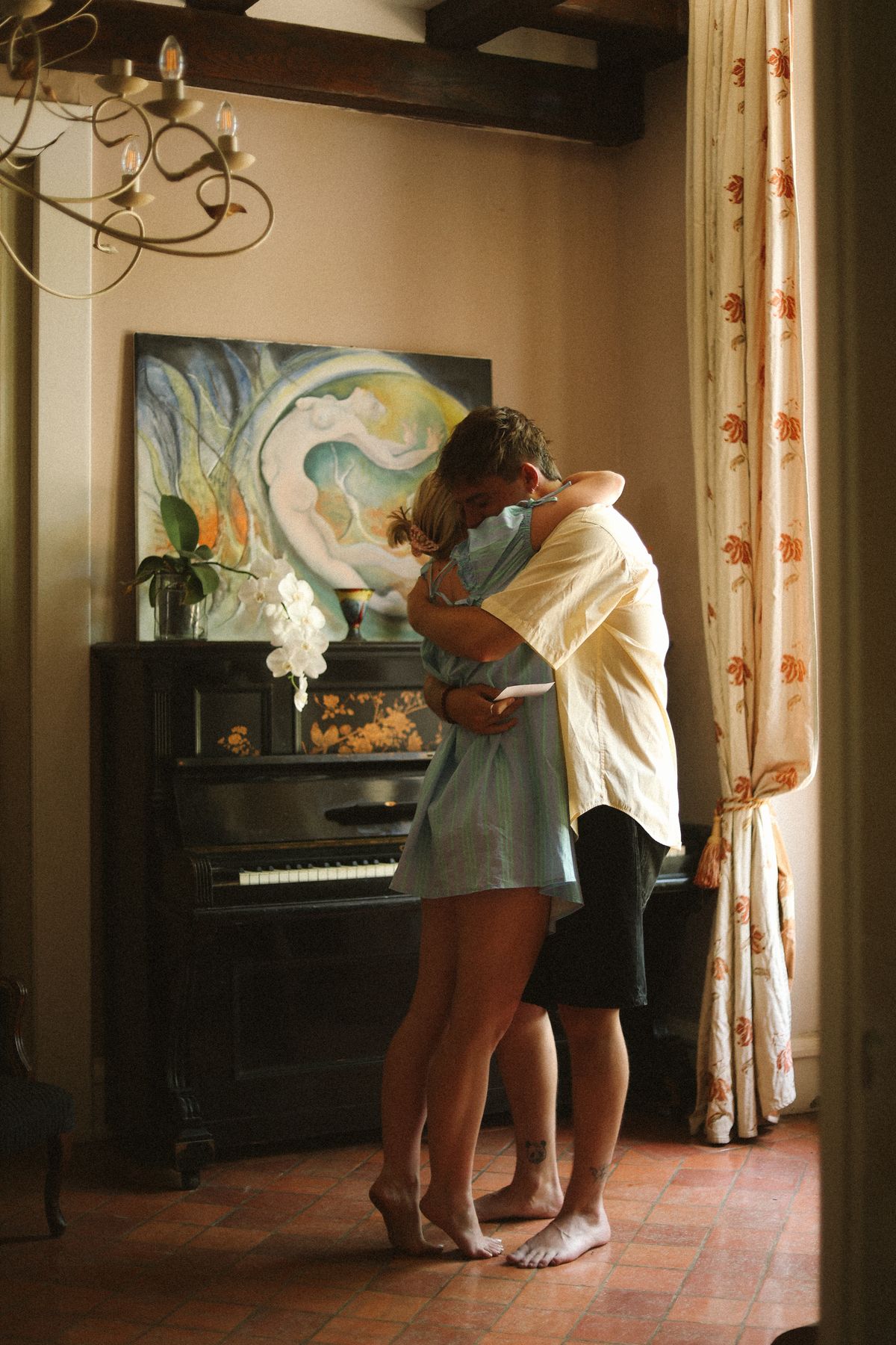 Couple embracing barefoot by piano at Chateau du Puits es Pratx, Ginestas