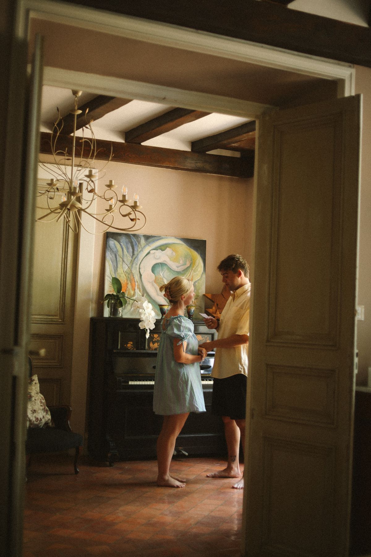 Couple reading note by painted piano at Chateau du Puits es Pratx, Ginestas