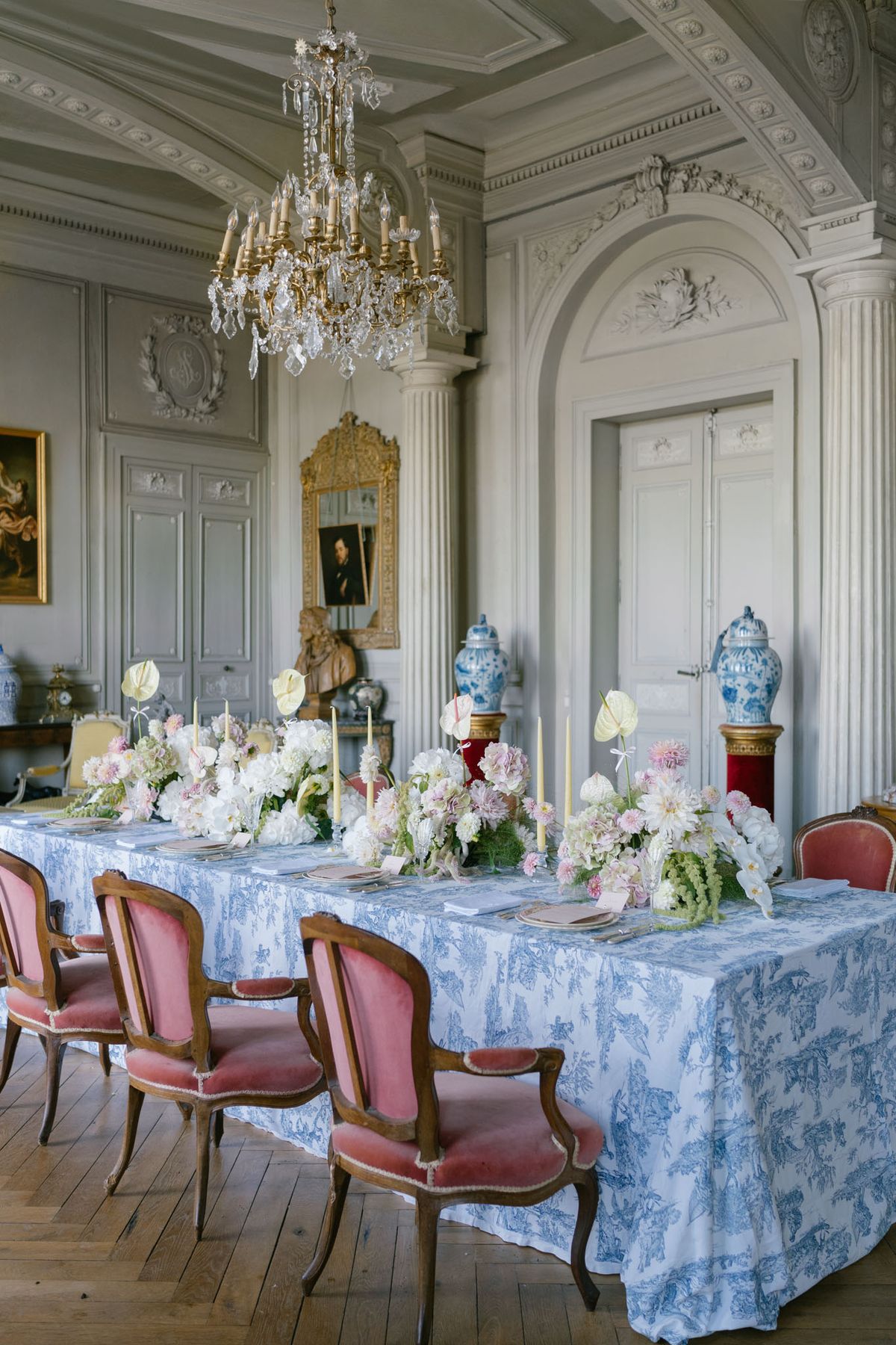 Chateau ballroom reception with toile de Jouy linen, rose velvet chairs, and white dahlia centerpieces