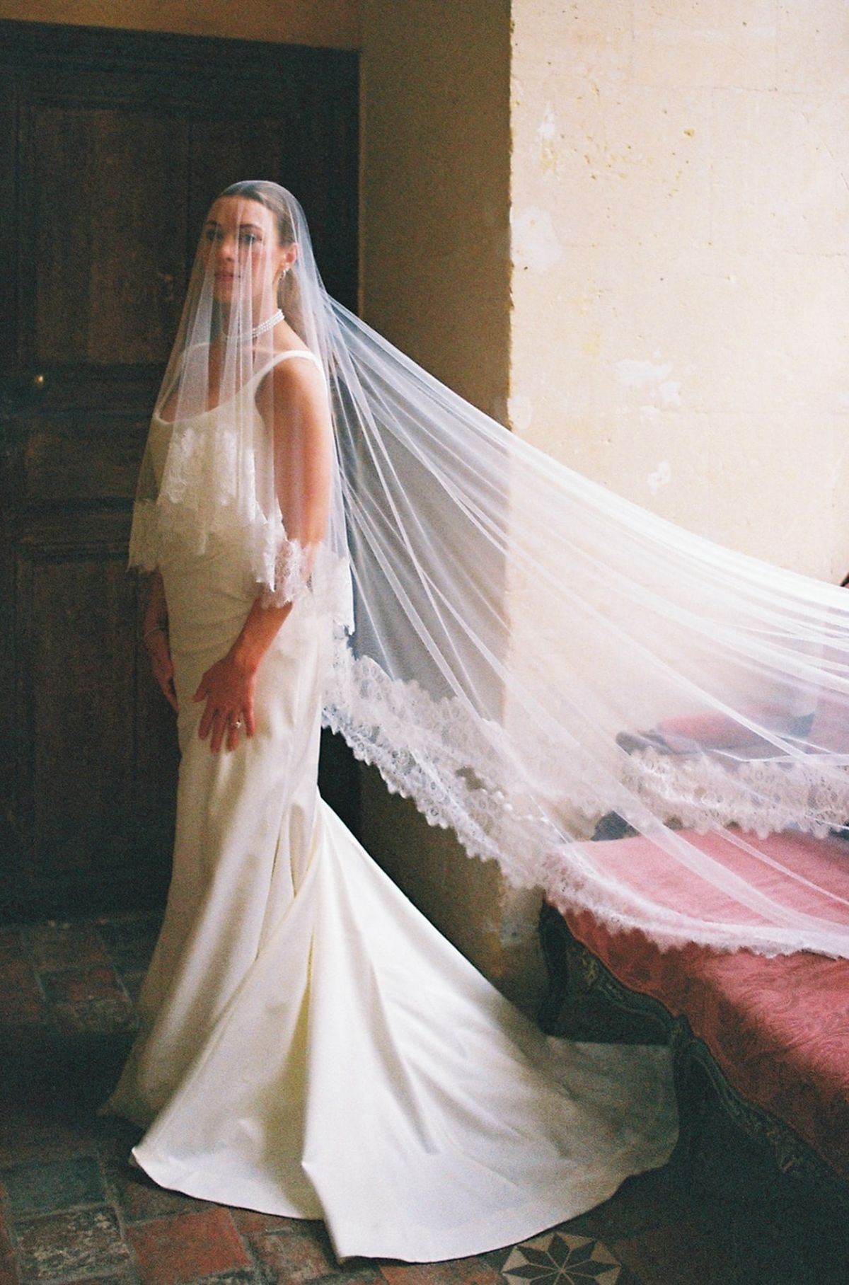 Film portrait of bride with cathedral lace veil pulled forward over her face