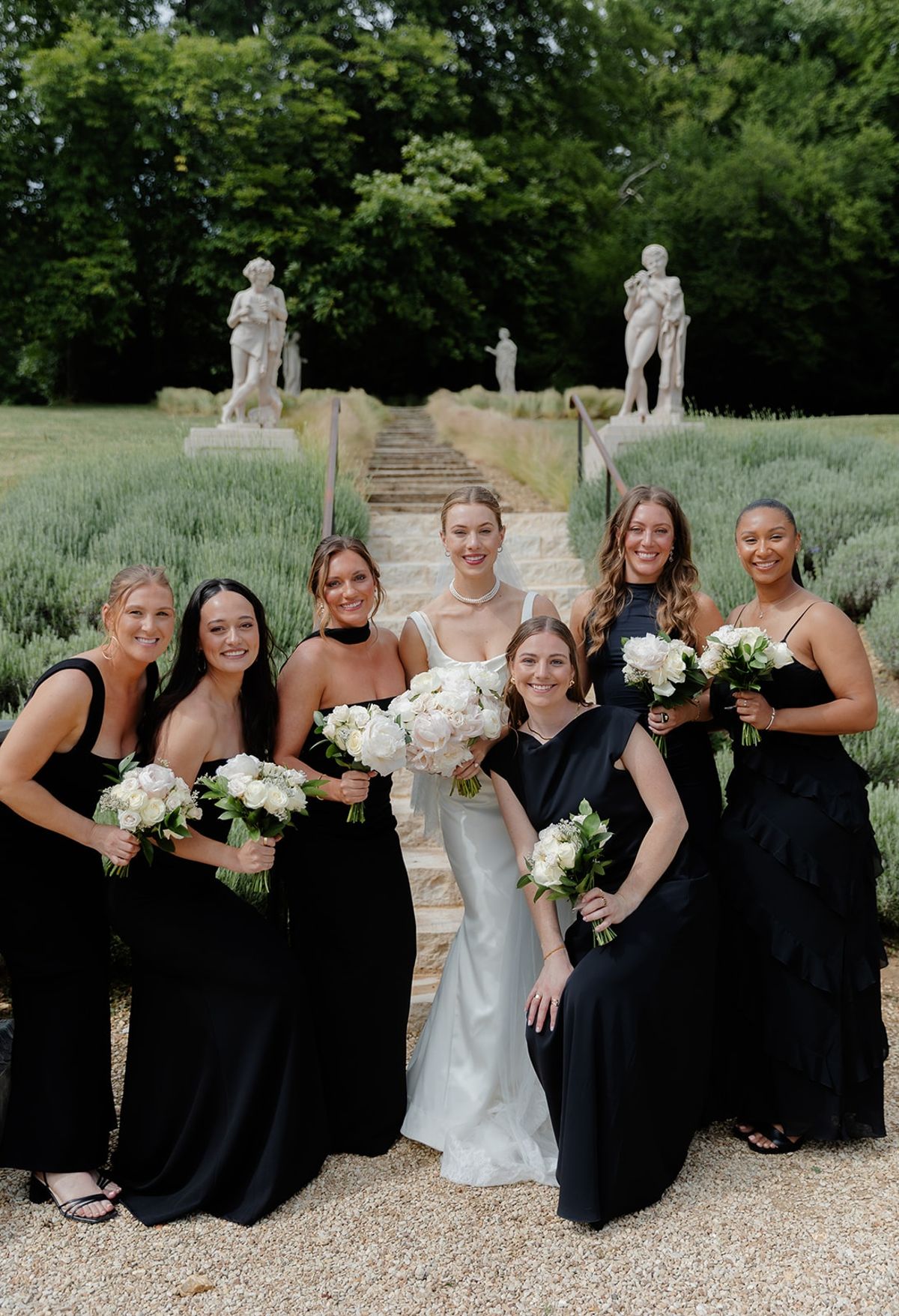Close portrait of bride and six bridesmaids in black holding white bouquets