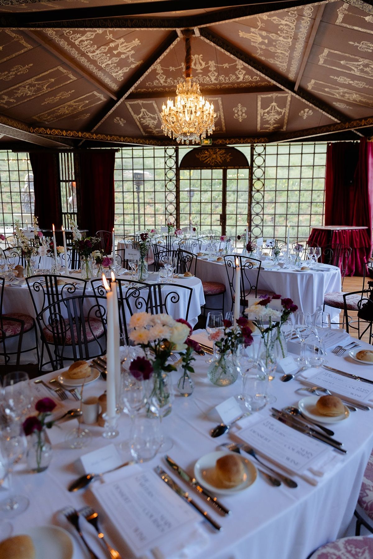 Dinner room glows under crystal chandelier and frescoed ceiling with set tables