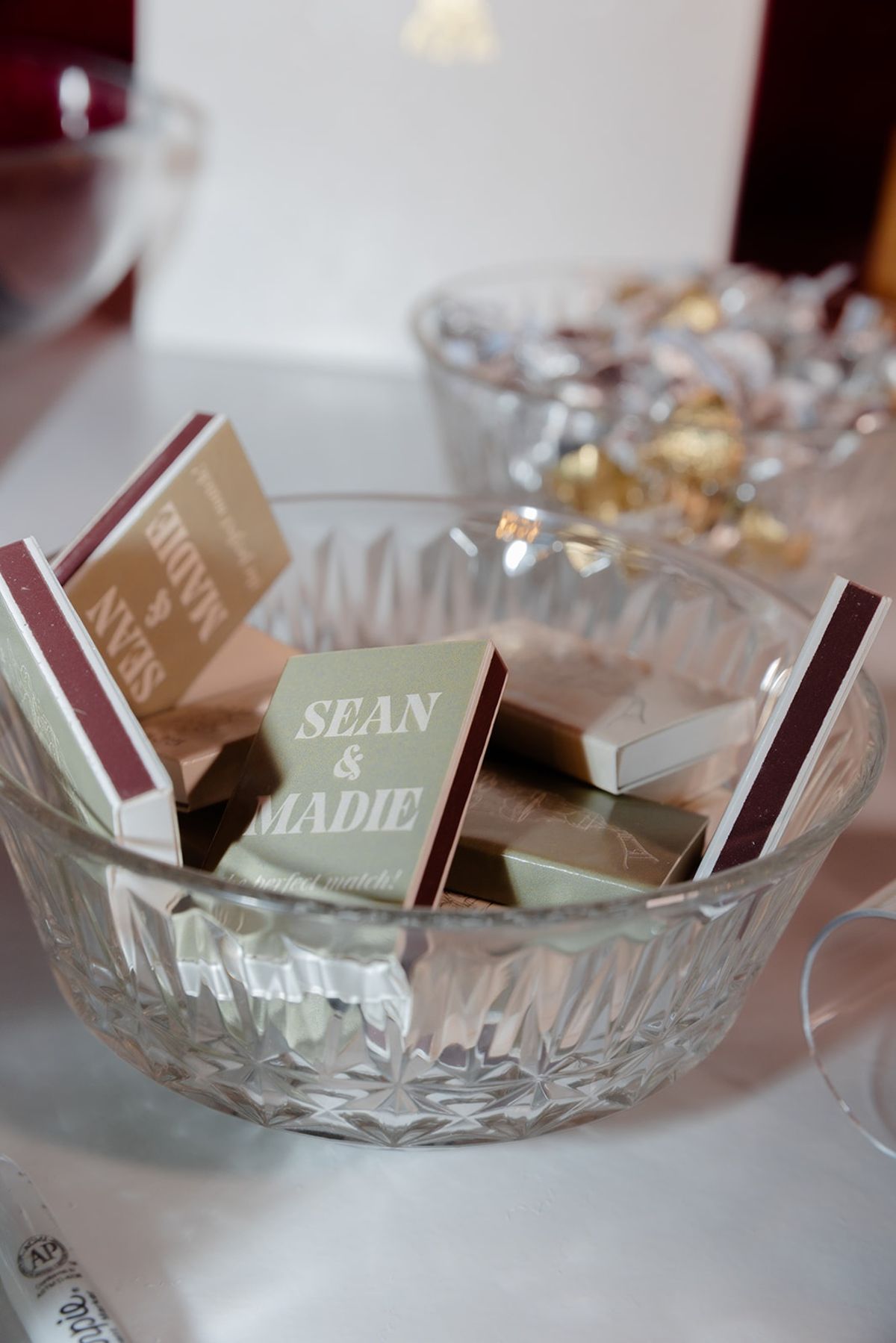 Crystal bowl of bespoke matchbox favours printed with couple's names on linen