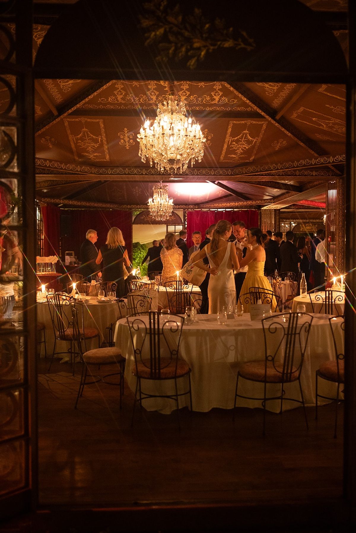 View through doorway into dinner pavilion as guests gather under crystal chandelier
