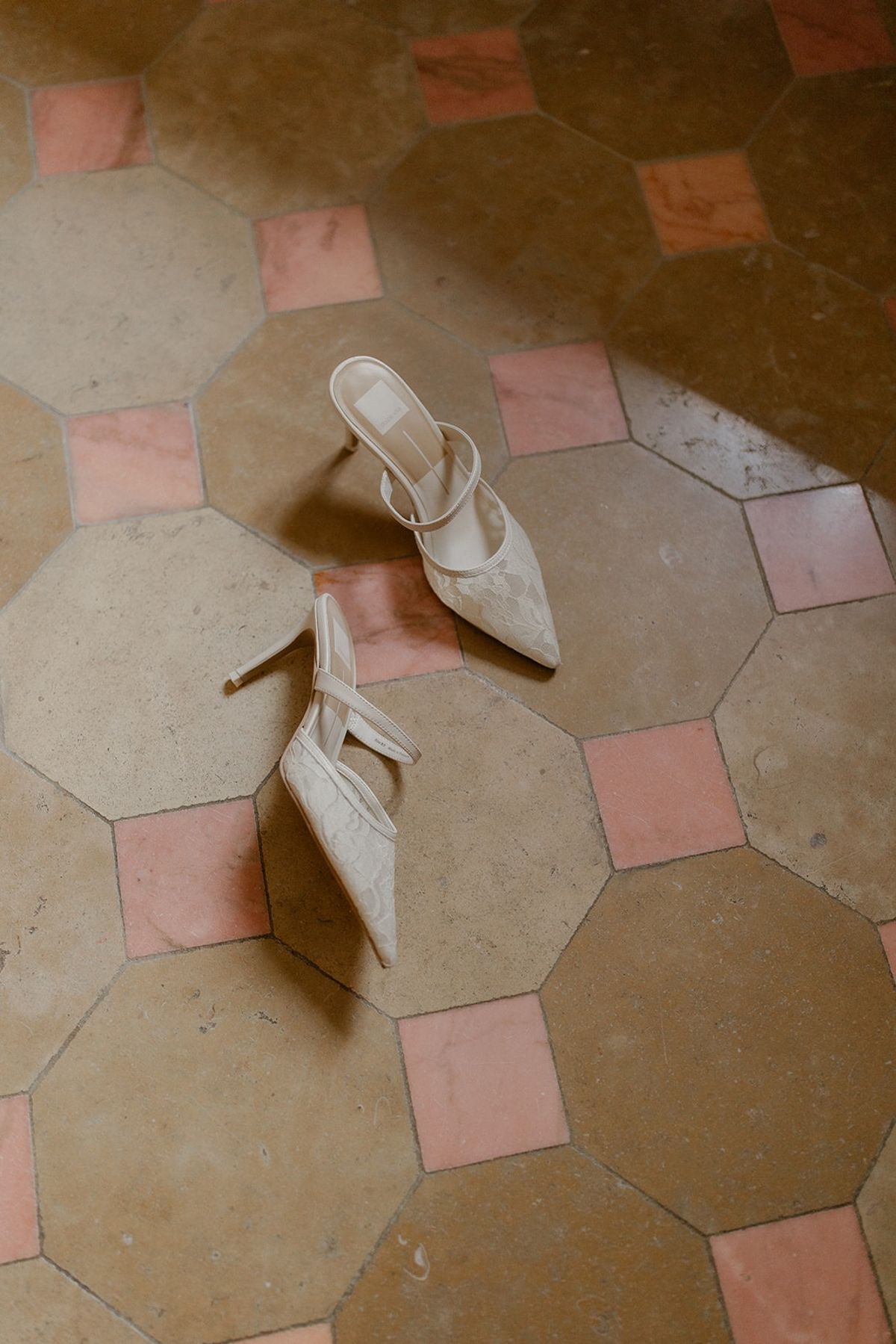 Lace bridal heels on pink and ochre octagonal tiled floor at a French chateau